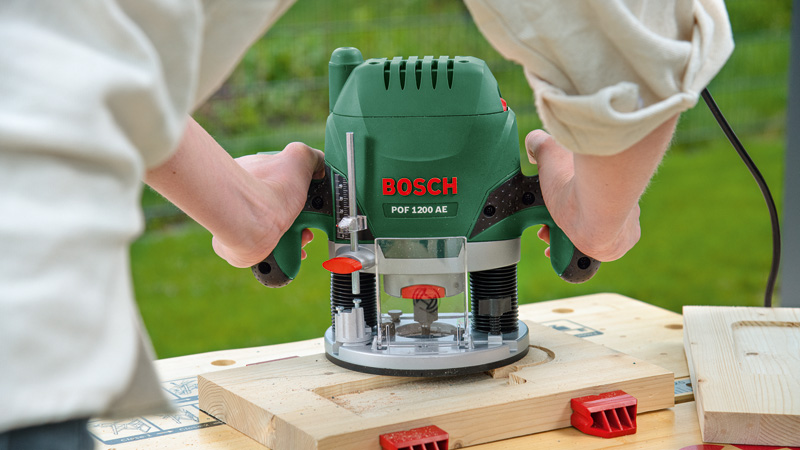 Fresatrice Bosch verde tenuta dalle mani per intagliare il legno.