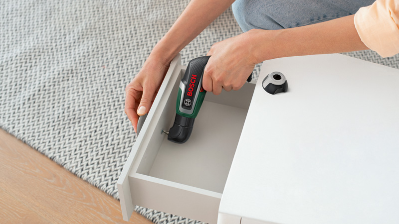 Persona atornilla en cajón blanco con destornillador inalámbrico Bosch.