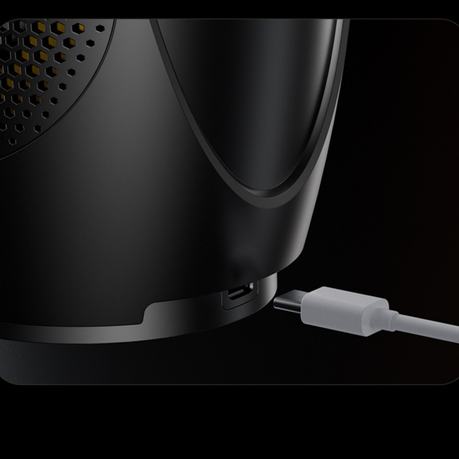 Ein weißes USB-C-Kabel wird in ein schwarzes Gerät mit Wabenmuster gesteckt.