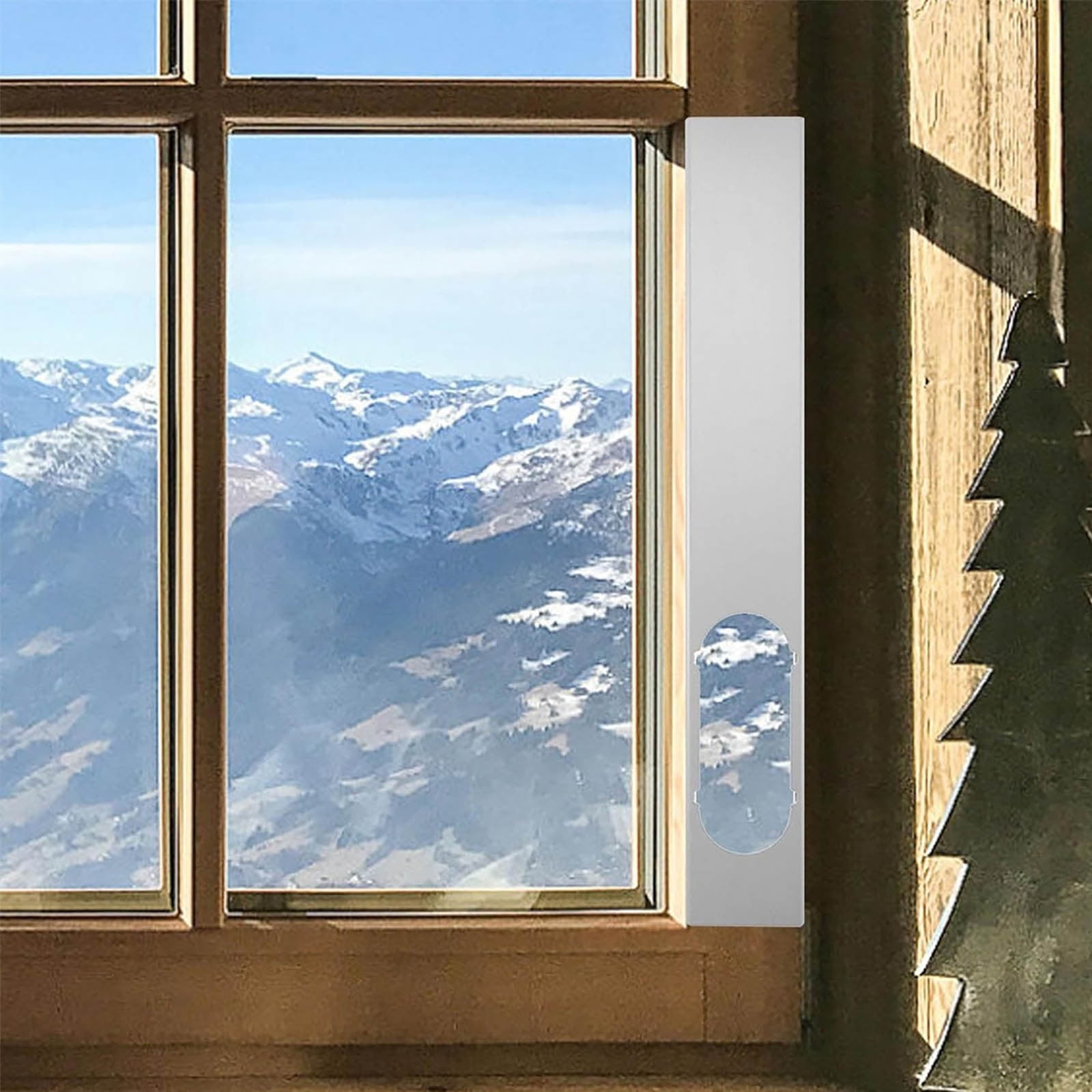 Holzfenster mit Blick auf verschneite Berge und blauen Himmel.