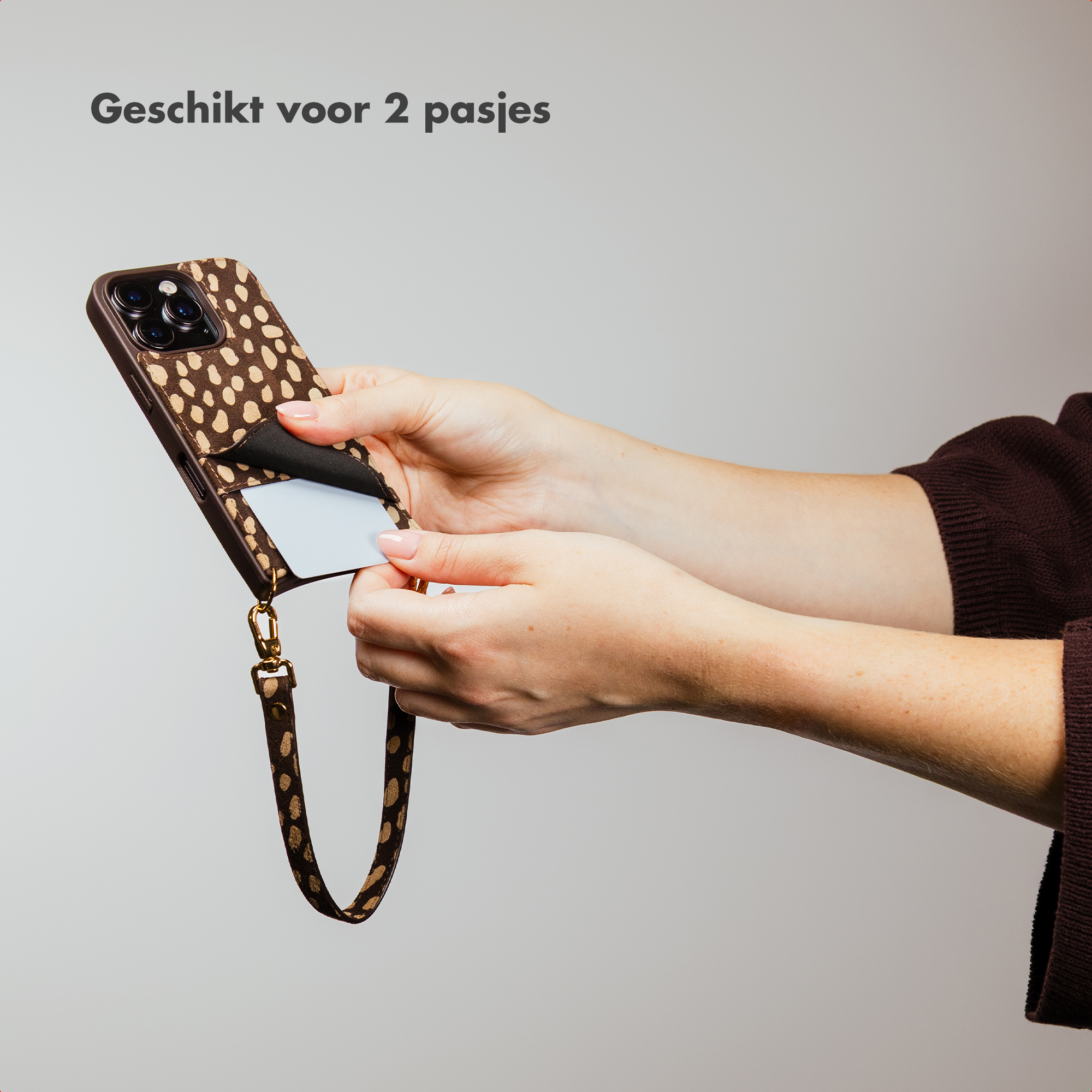 A hand inserts a card into a leopard-print phone case.