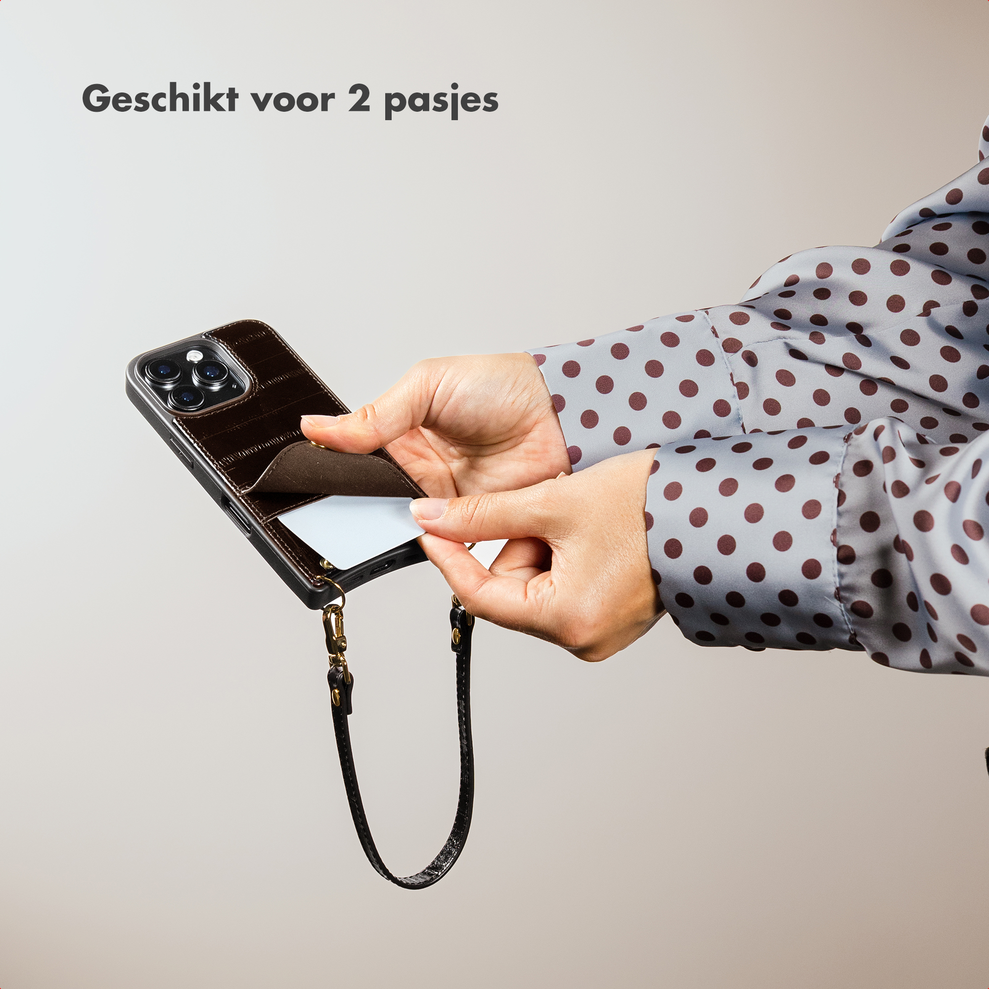 Brown phone case with card slot being used by a person in a polka dot shirt.