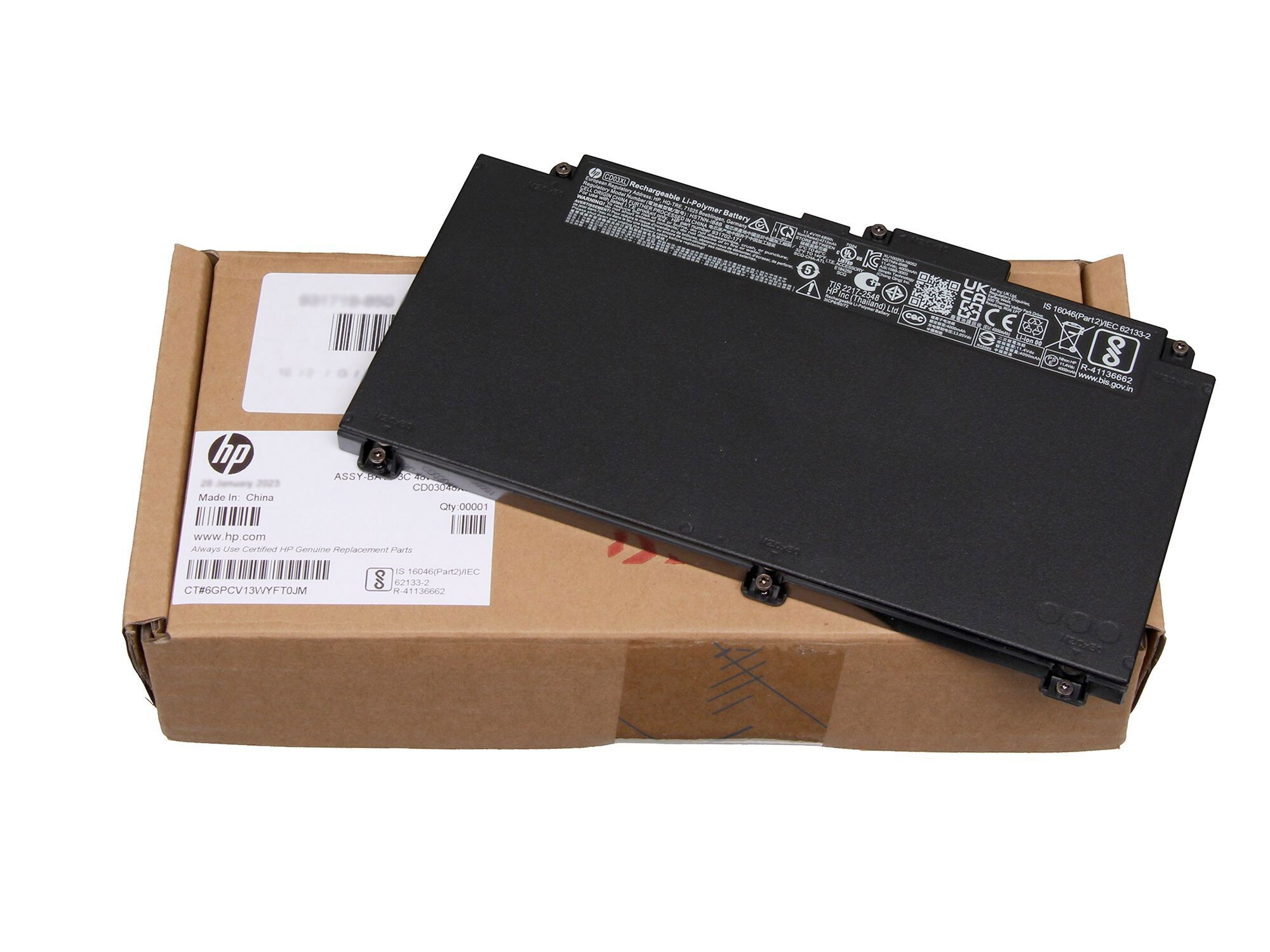 Schwarzer HP Laptop-Akku liegt auf brauner Verpackung. Details sind auf dem Akku und der Verpackung sichtbar.