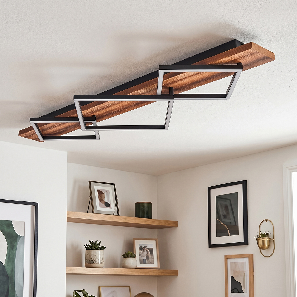 Ein moderner Deckenventilator mit Holz- und schwarzen Metallakzenten, über einem Regal.