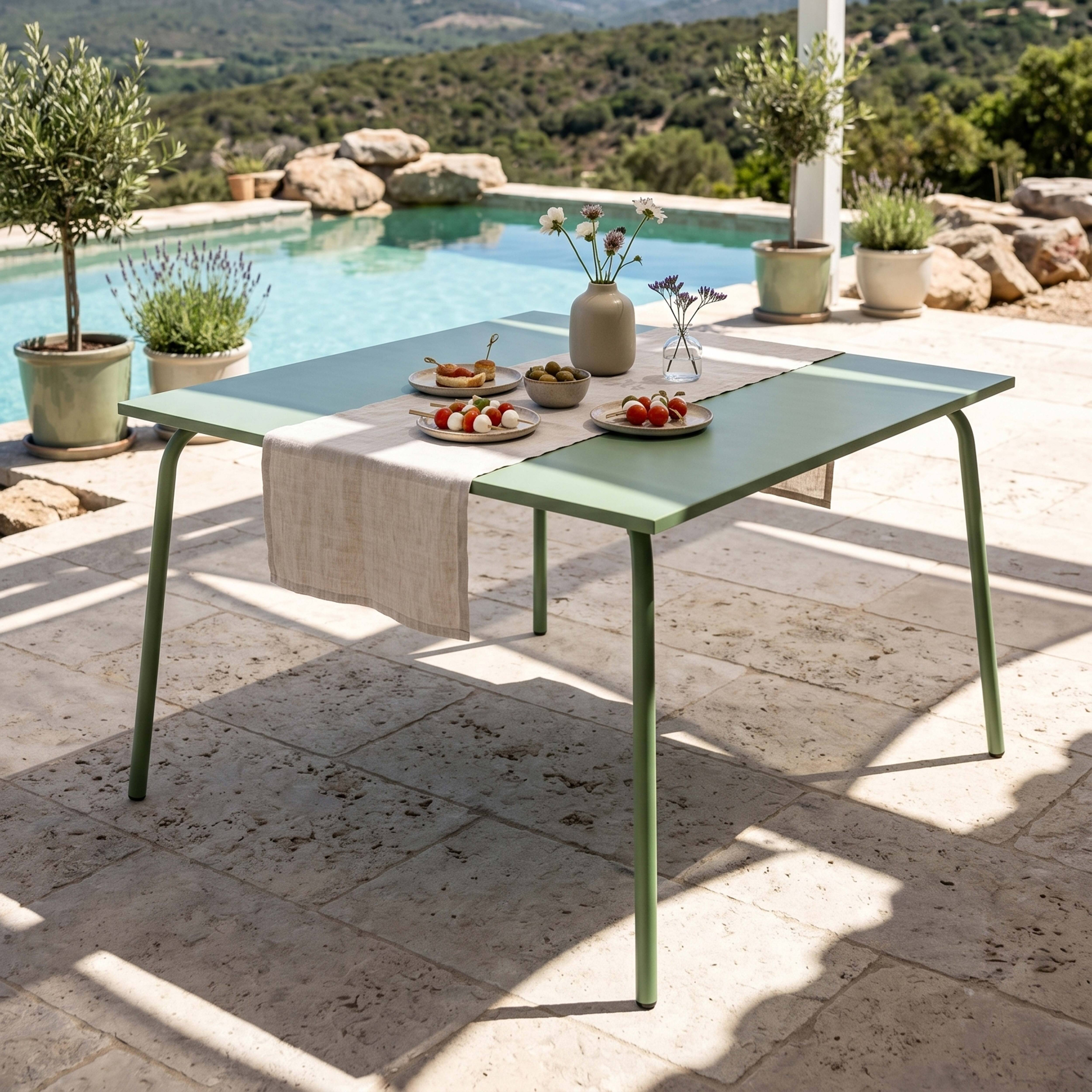 Ein grüner Tisch mit Essen und Blumen steht neben einem Pool.