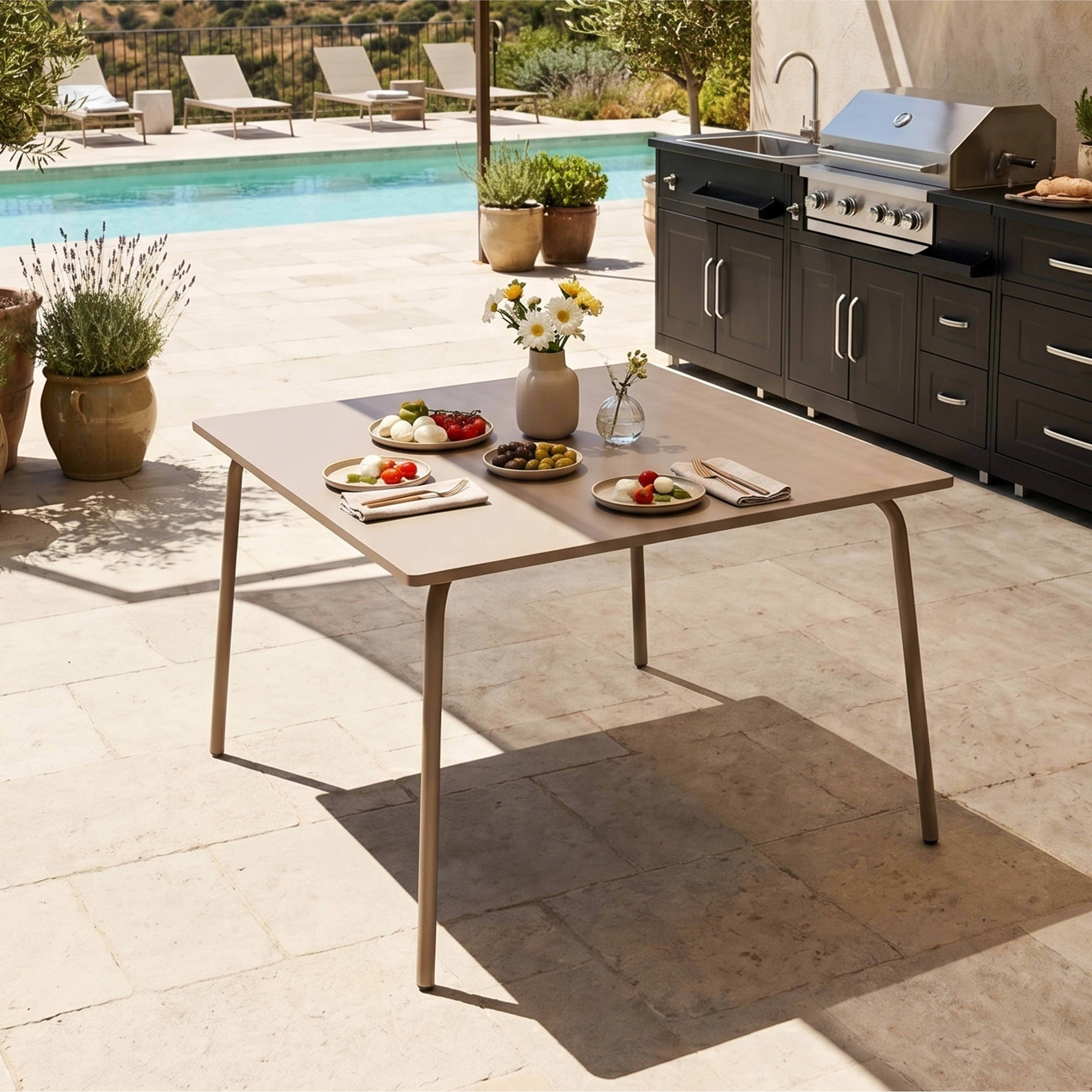 Ein Tisch mit Essen steht neben einem Grill und Pool mit Liegen.