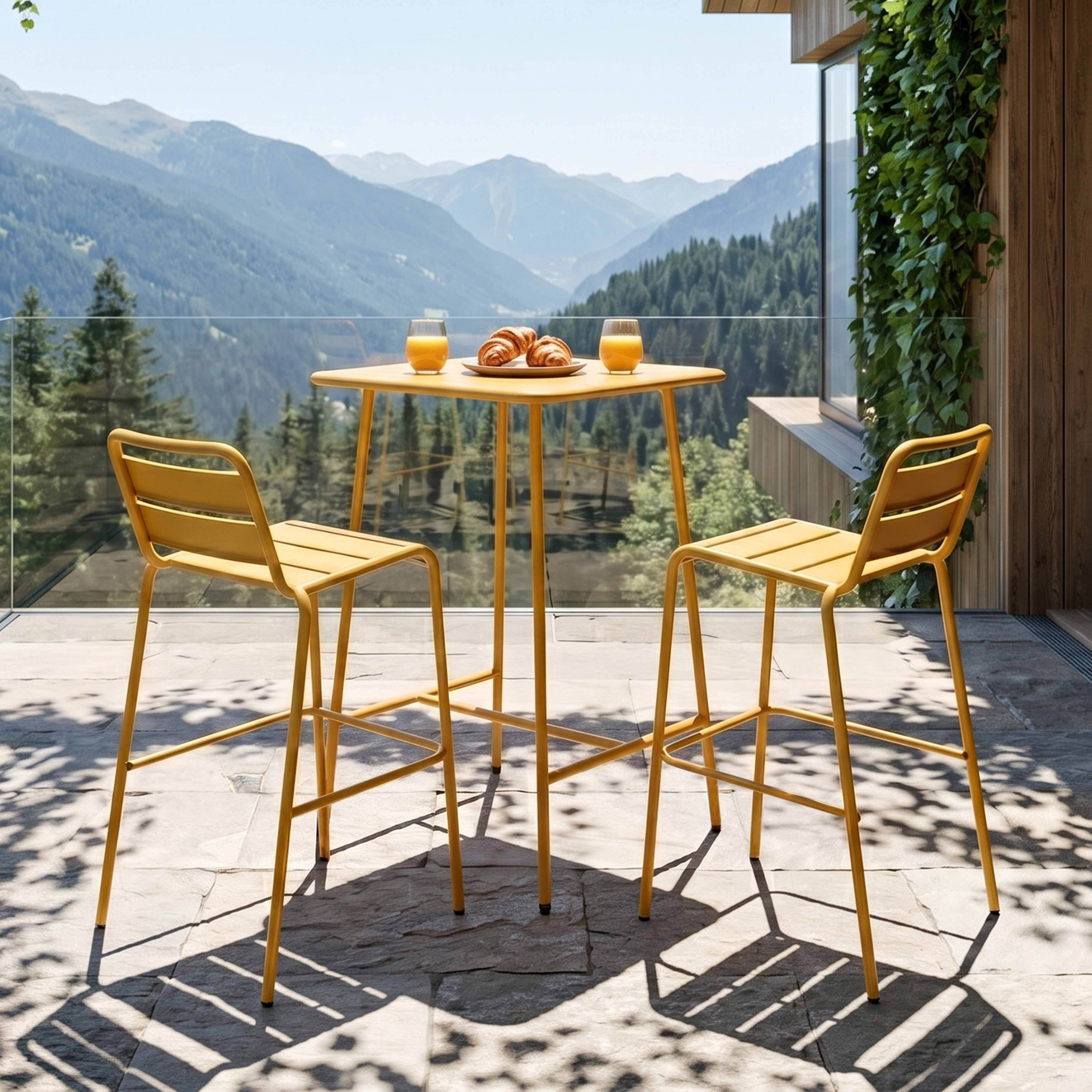 Gelbe Barhocker und Tisch mit Gebäck und Saft vor Bergkulisse.