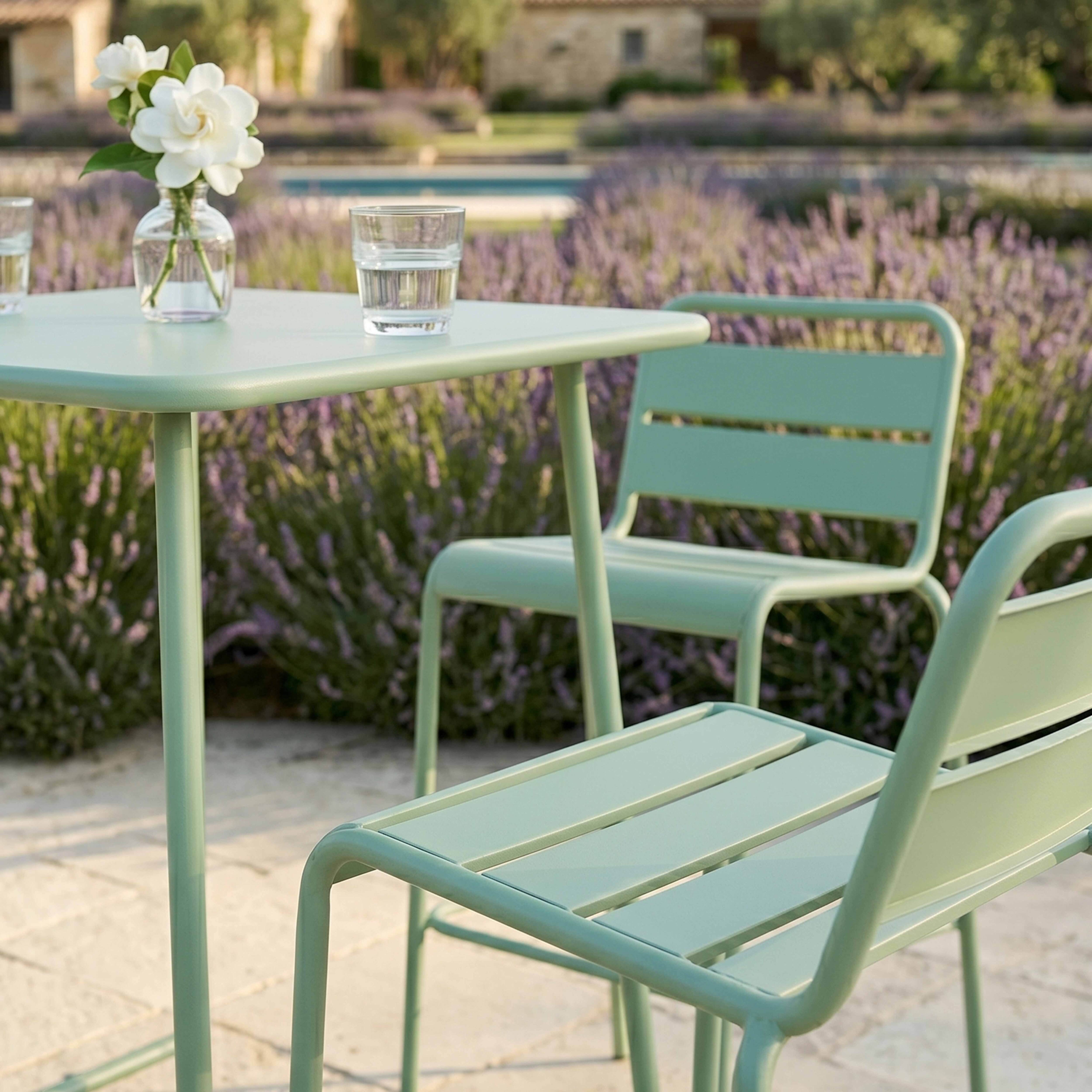 Grüne Gartenmöbel stehen auf einer Terrasse mit Lavendel und einem Pool.