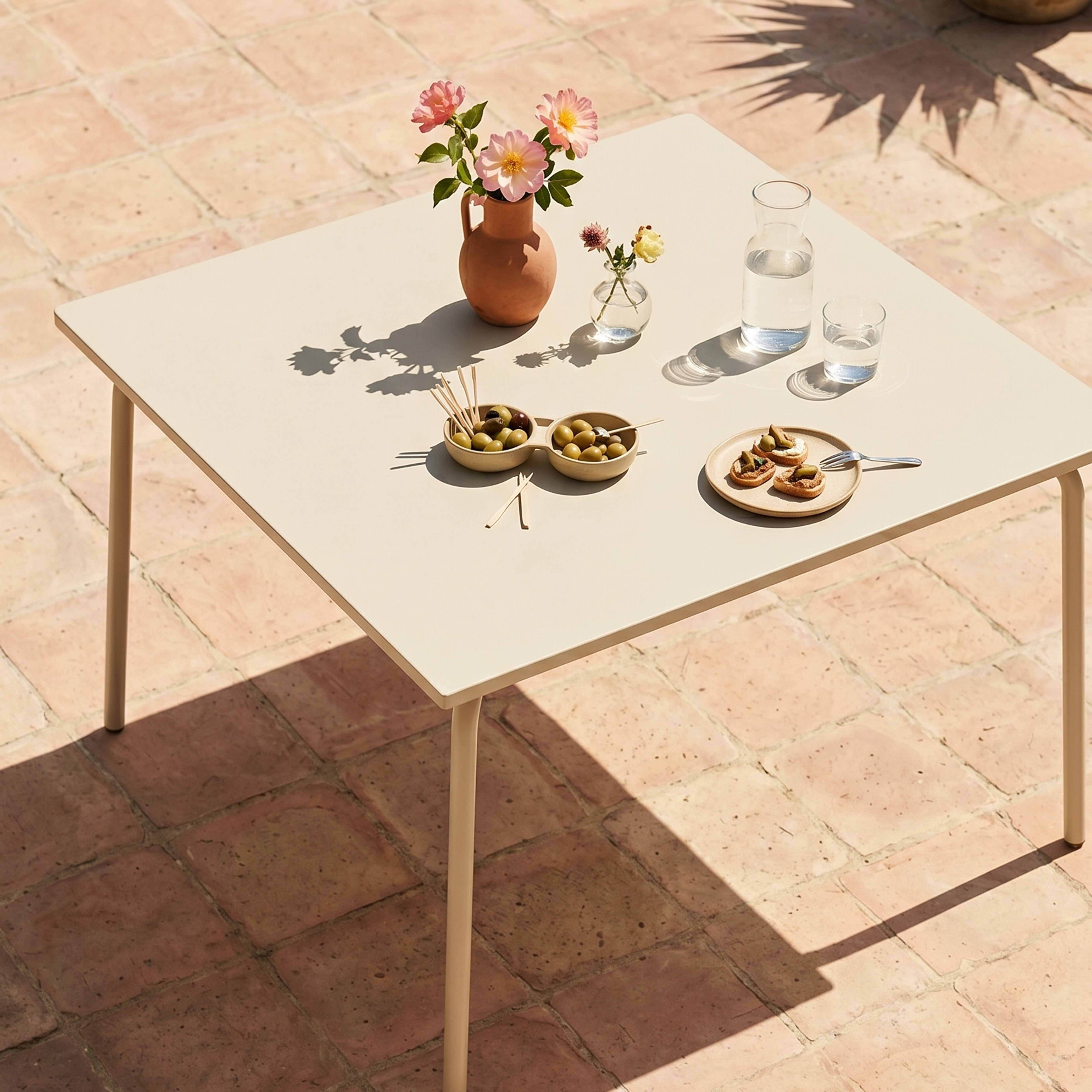 Ein Tisch mit Blumen, Oliven, Snacks und Getränken auf einer Terrasse.