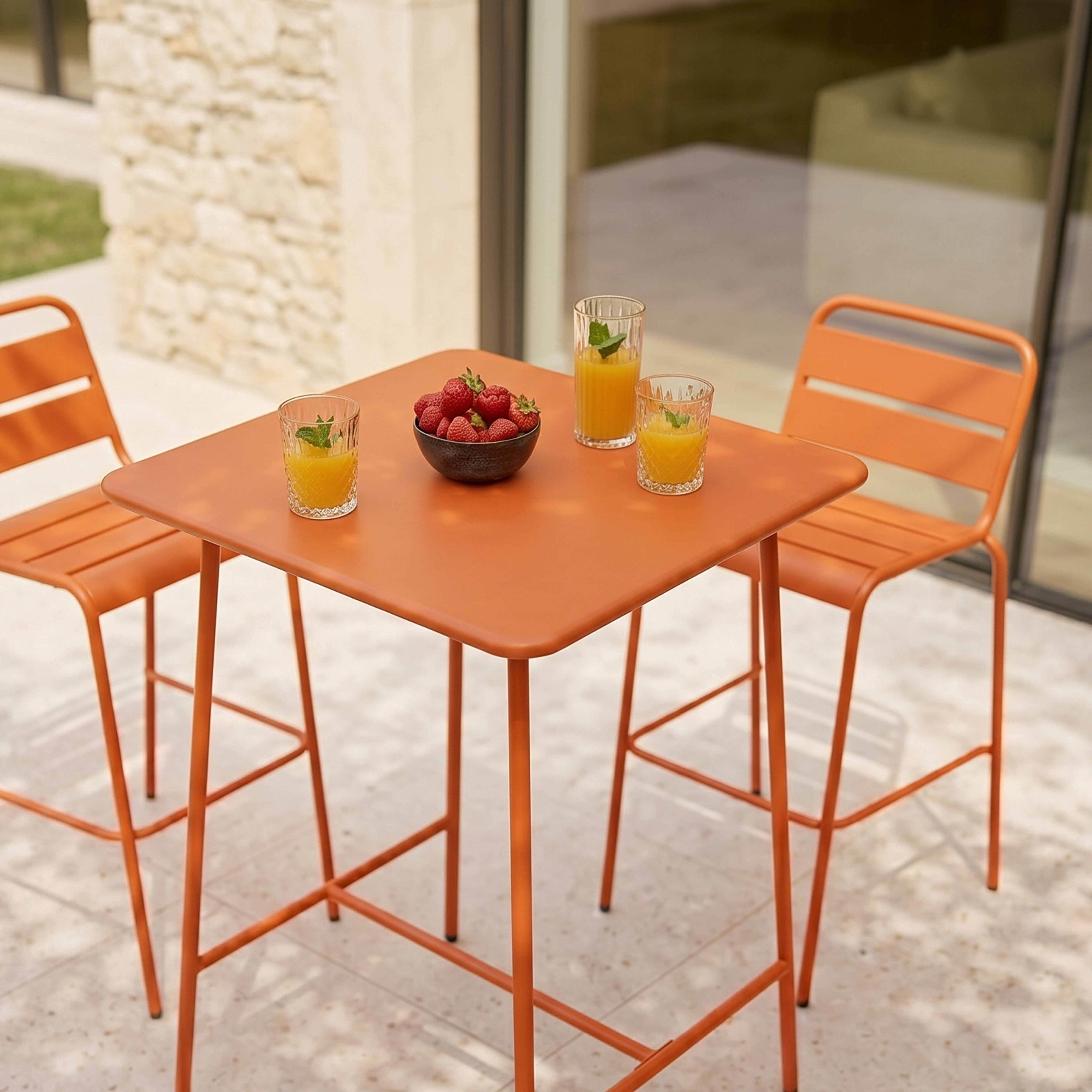 Ein orangefarner Bistrotisch mit zwei Hockern, garniert mit Erdbeeren und Saft.