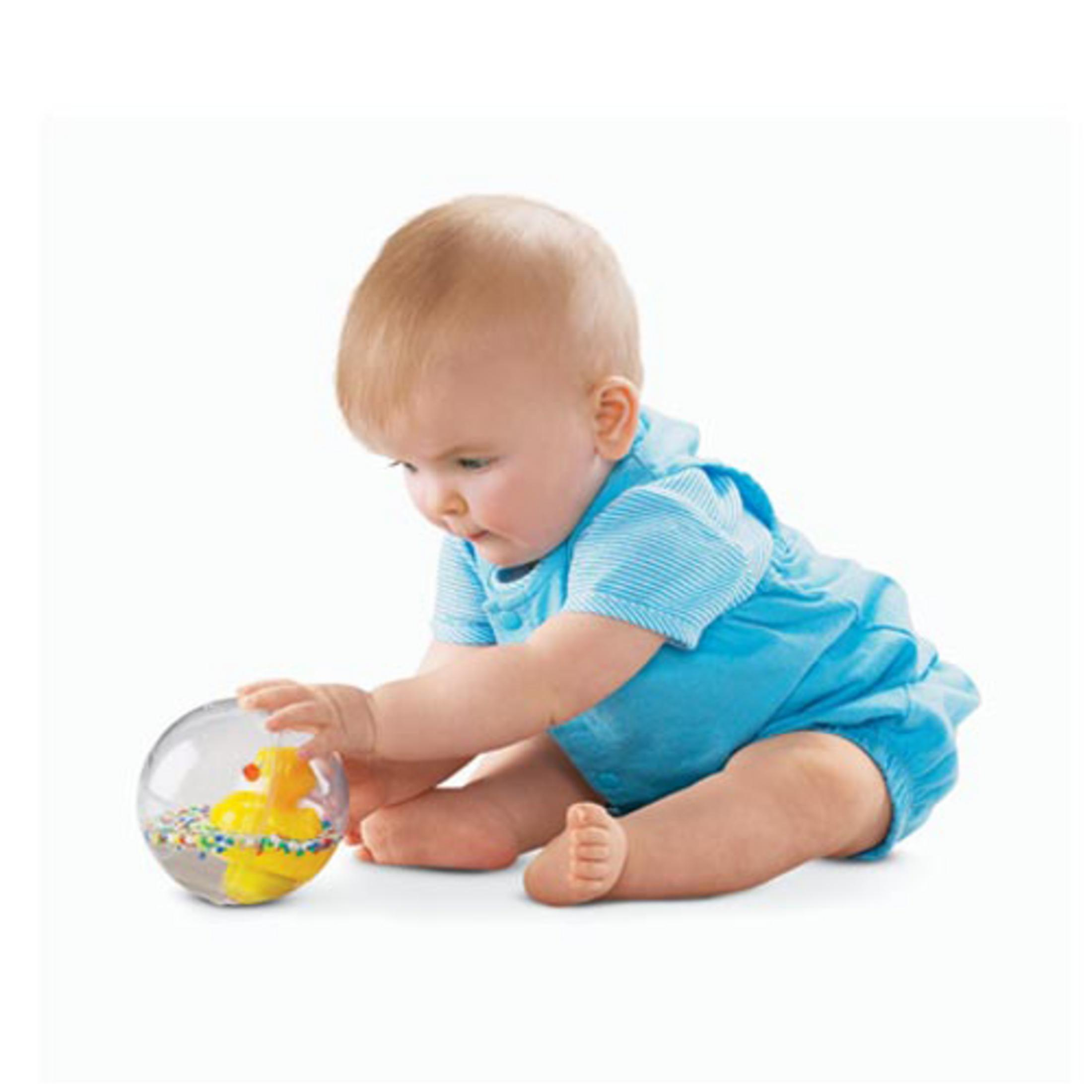 Ein Baby in blauer Kleidung spielt mit einer durchsichtigen Kugel mit gelber Ente.
