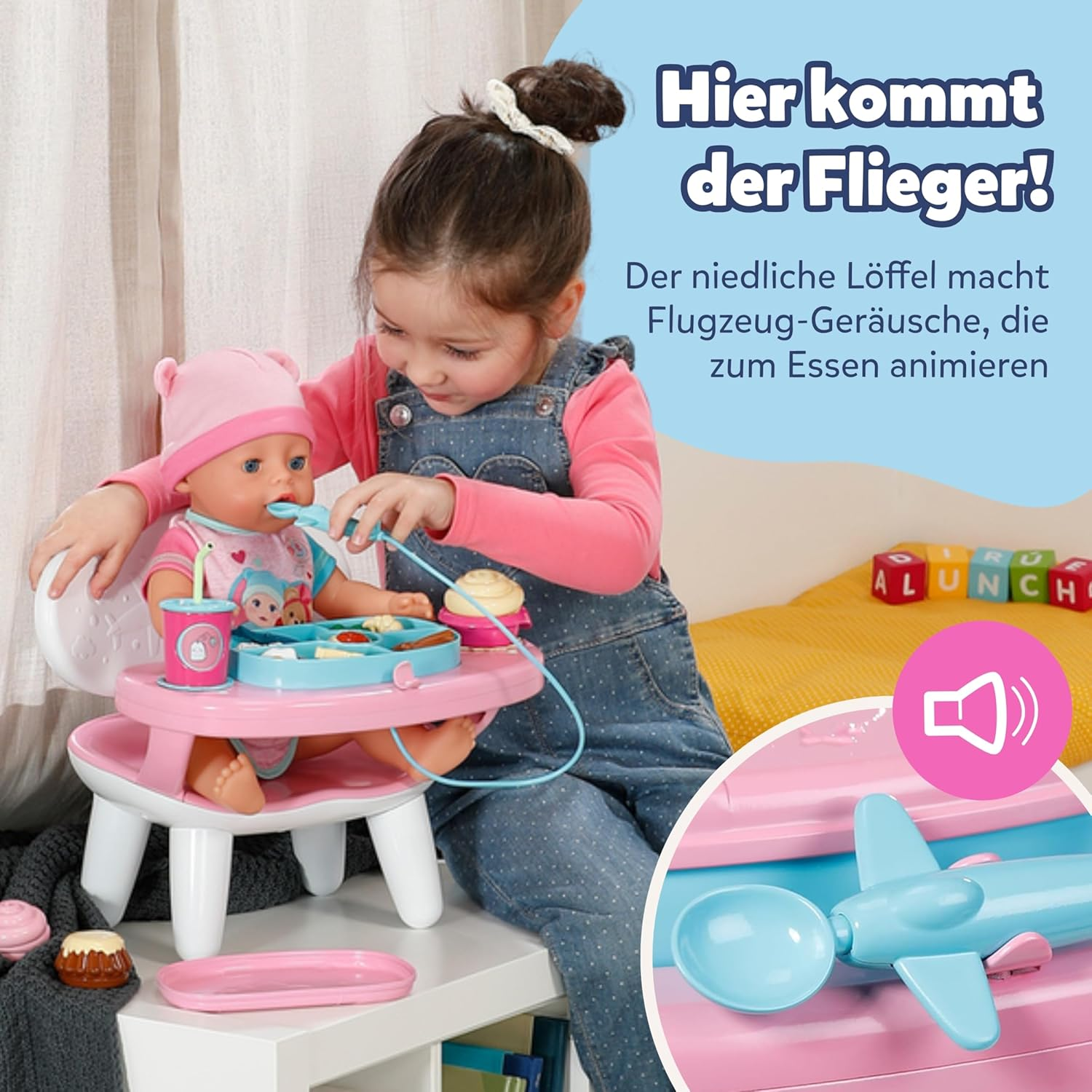 Ein Mädchen füttert eine Puppe mit einem Löffel, der wie ein Flugzeug aussieht.