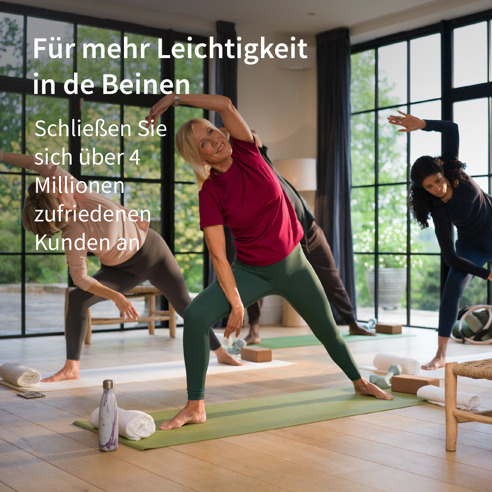 Frauen machen Yoga in einem hellen Raum mit großen Fenstern.