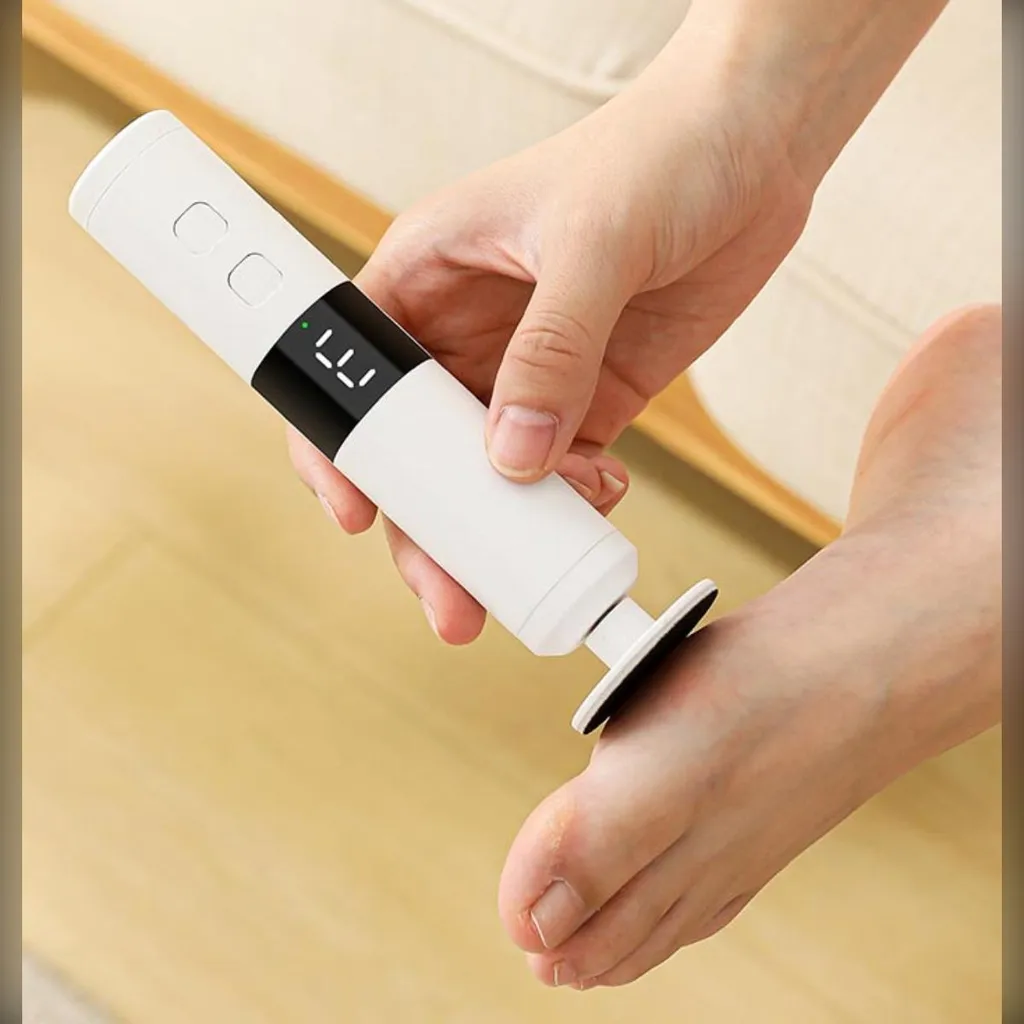Eine Hand hält einen weißen elektrischen Hornhautentferner an einen nackten Fuß mit Digitalanzeige.