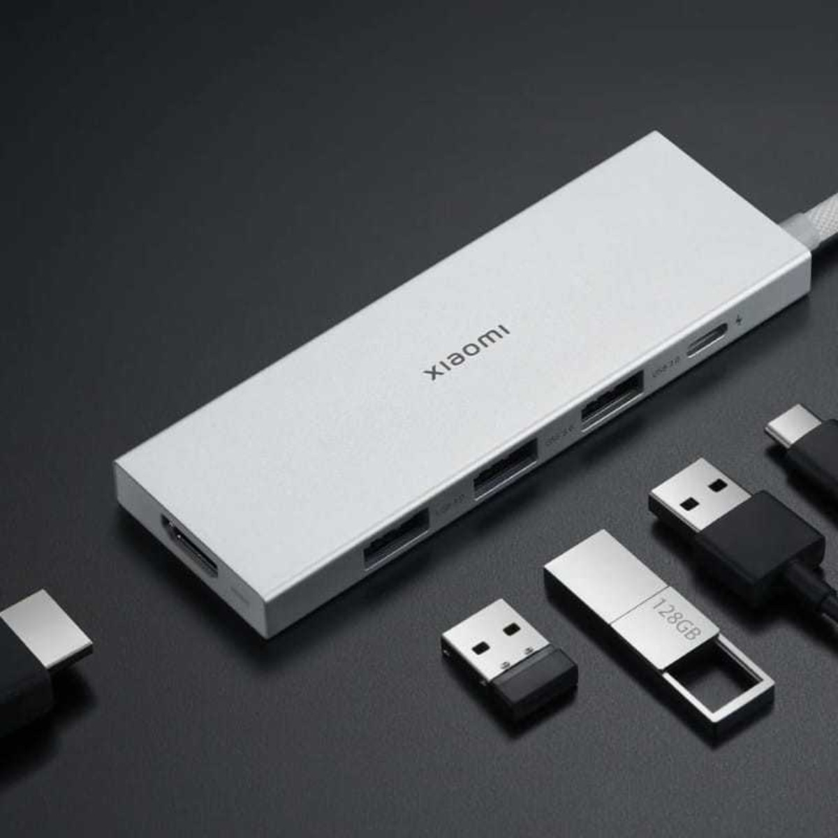 Un hub USB-C plateado de Xiaomi con varios puertos y unidades USB sobre fondo negro.
