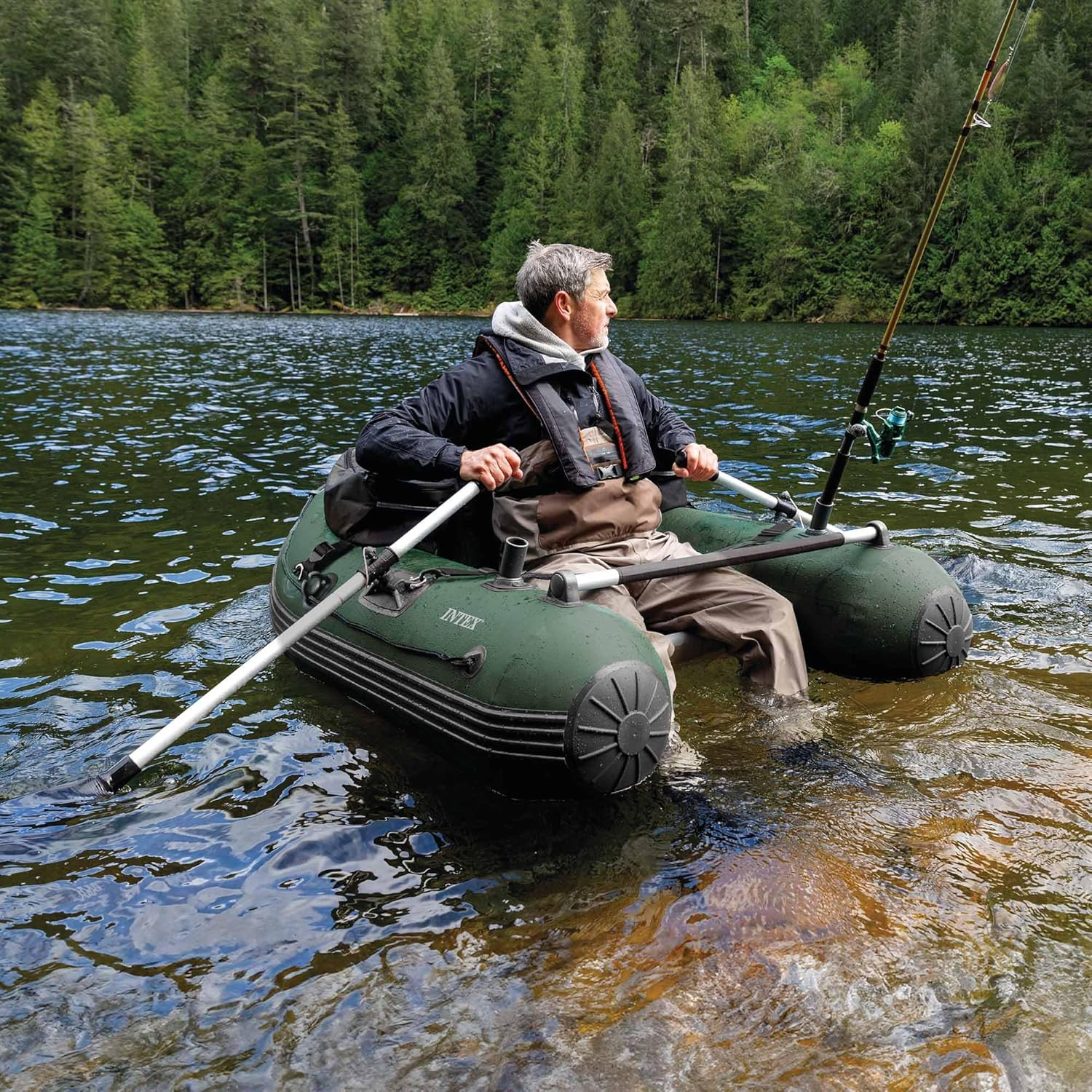 Mann in Schlauchboot angelt auf einem See mit Bäumen im Hintergrund.