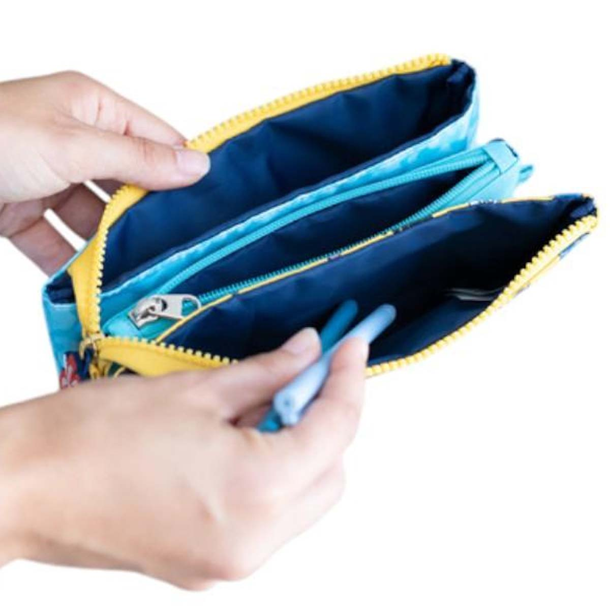 Hände öffnen eine blaue Tasche mit gelbem Reißverschluss, um Stifte hineinzulegen.
