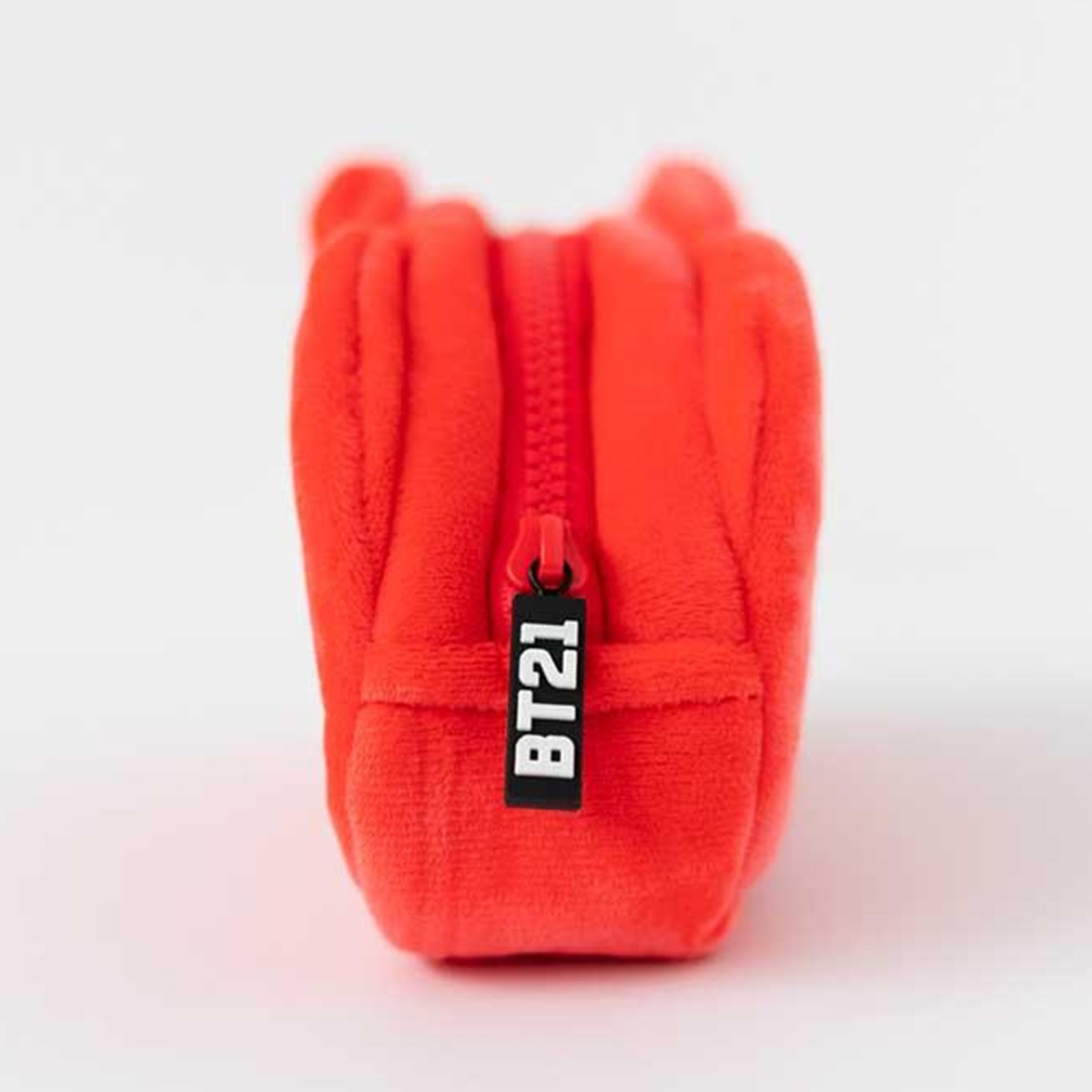 Ein roter Plüschbeutel mit Reißverschluss und "BT21"-Anhänger.