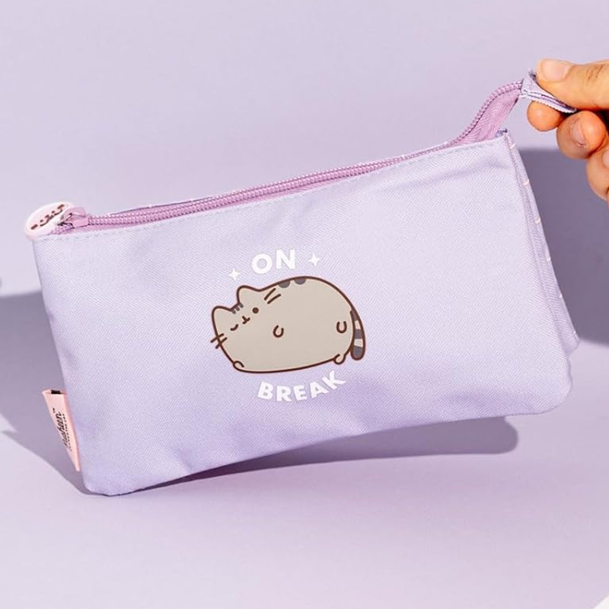 Eine lavendelfarbene Tasche mit einem pummeligen Kätzchen-Aufdruck, das auf dem Bauch liegt.