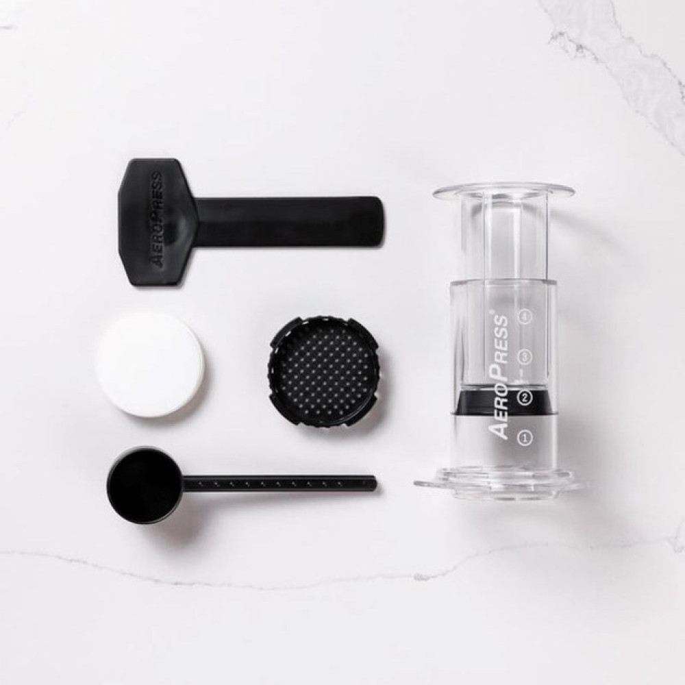 Ekspres do kawy Aeropress z akcesoriami na marmurowym tle.