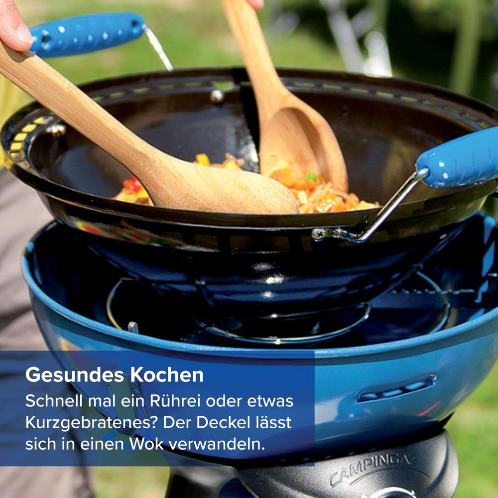 Zwei Holzlöffel rühren Gemüse in einem Wok auf einem blauen Grill.