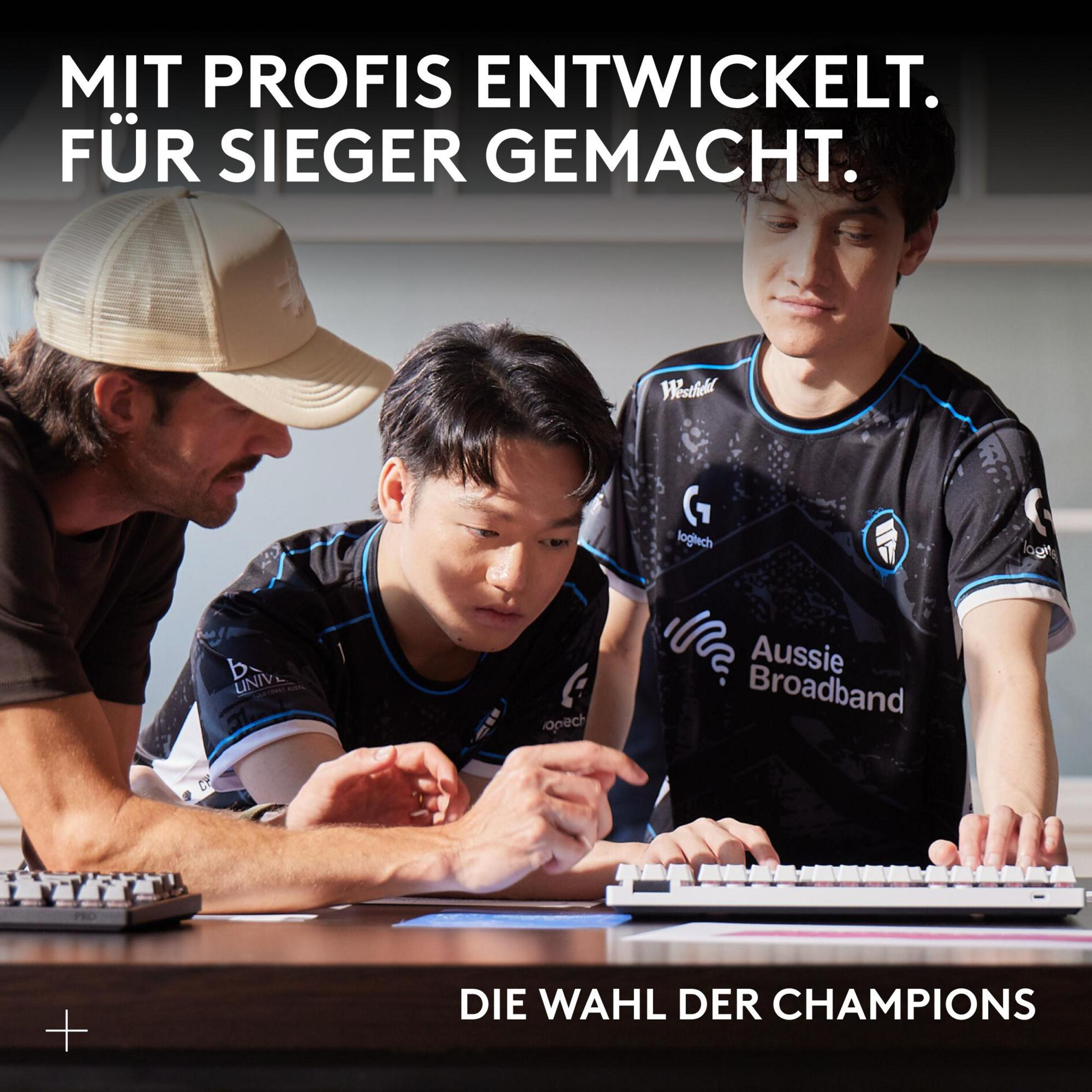 Drei Männer blicken auf eine Tastatur, zwei tragen Gaming-Shirts. Text: Mit Profis entwickelt.
