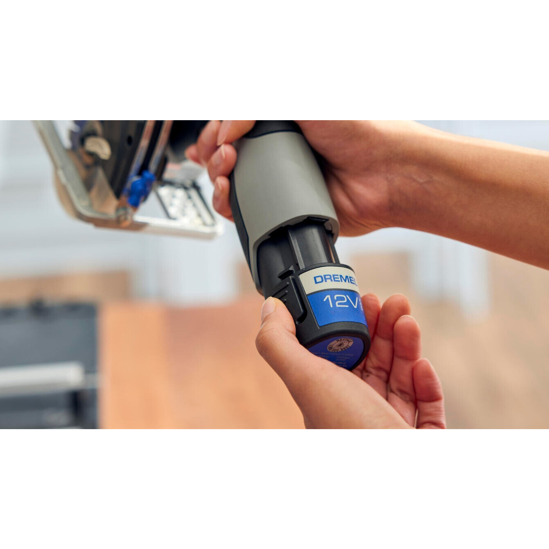 Hände setzen eine 12V Dremel-Batterie in ein Werkzeug ein.