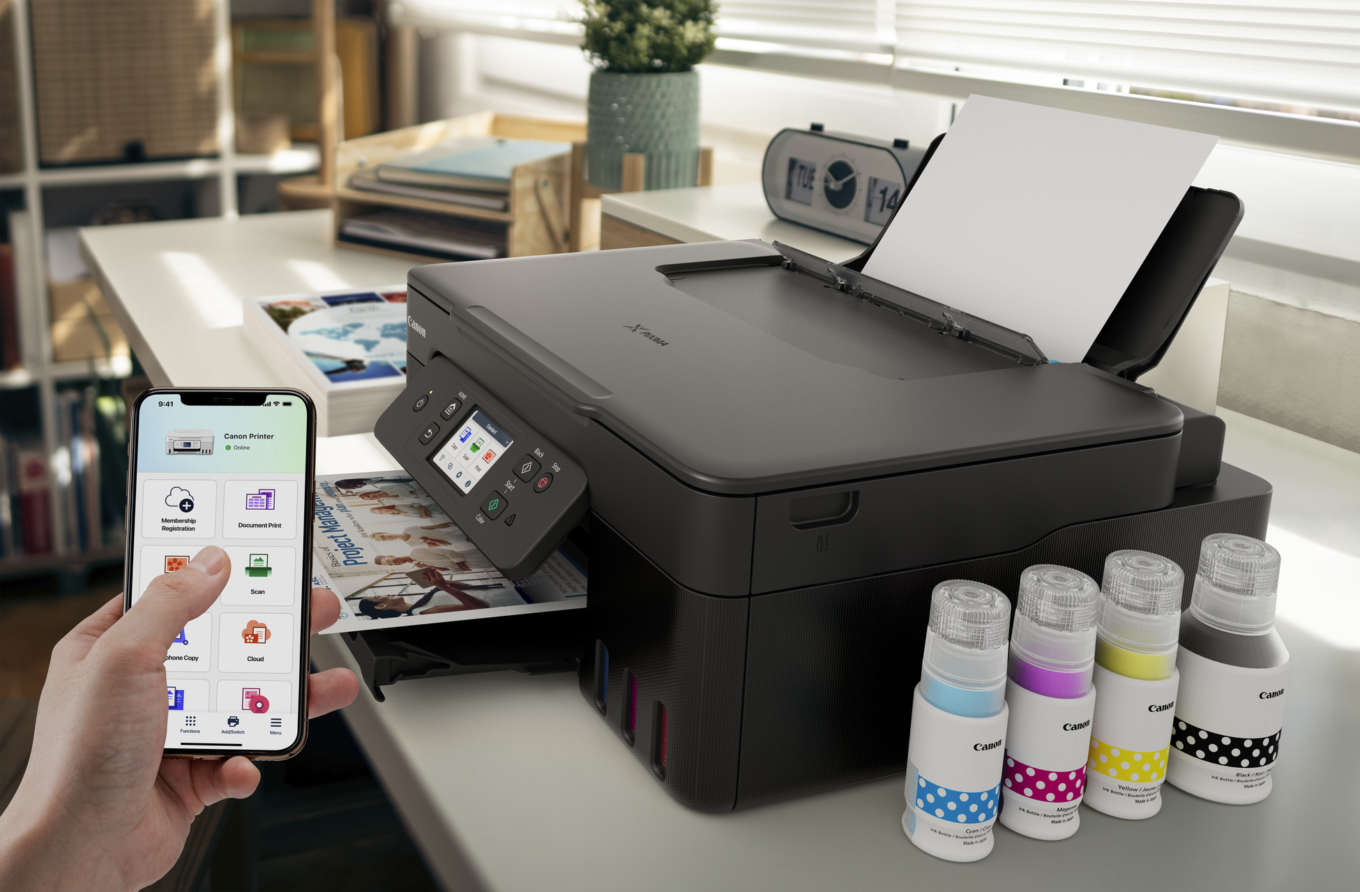Ein Smartphone zeigt eine Drucker-App, daneben ein Canon-Drucker mit Tinte.
