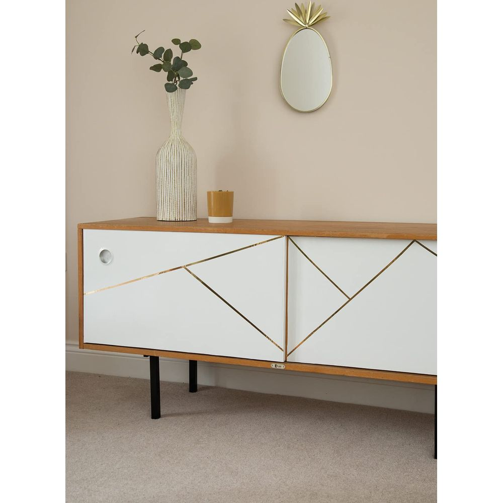 Ein weißer Schrank mit Holzoberseite, Keramikvase, Kerze und Ananasspiegel.