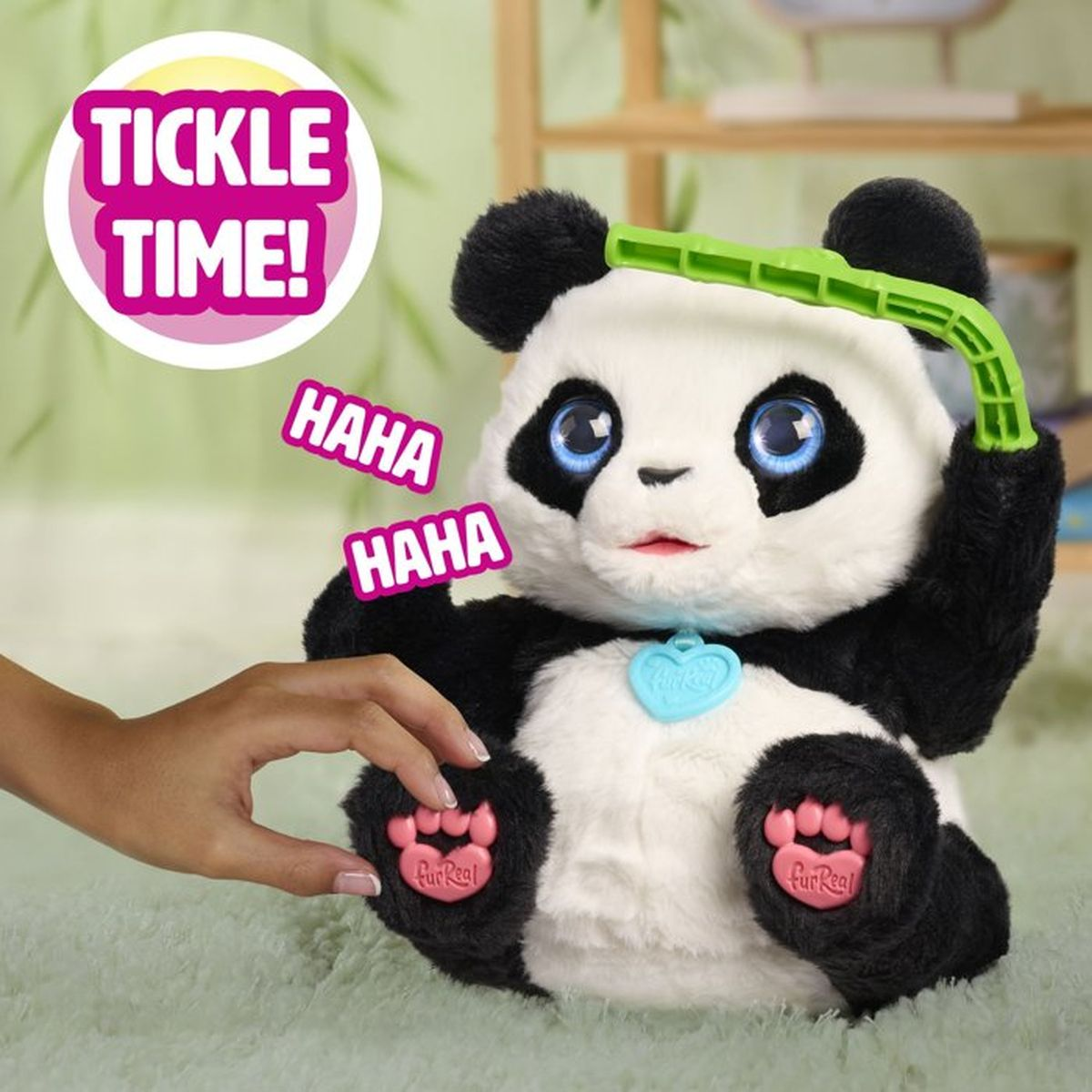 Un panda de peluche que sostiene un bambú de juguete verde es cosquilleado por una mano.