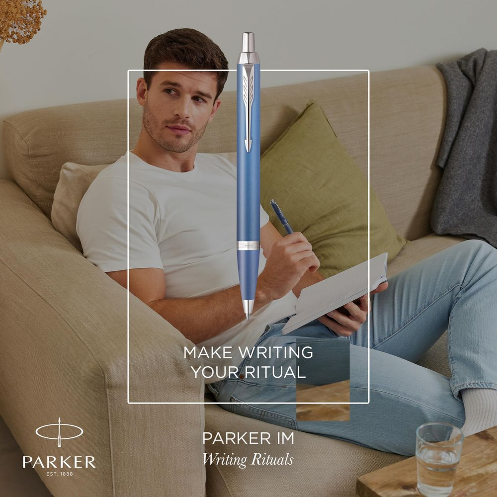Ein Mann sitzt auf einem Sofa und schreibt mit einem blauen Stift in ein Notizbuch.