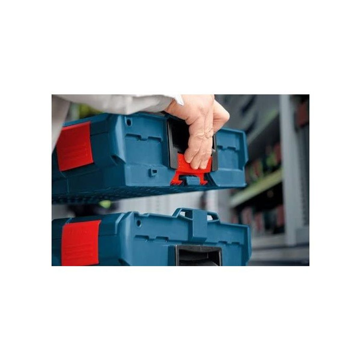 Eine Hand schließt zwei blaue Werkzeugkisten mit roten Verriegelungen.