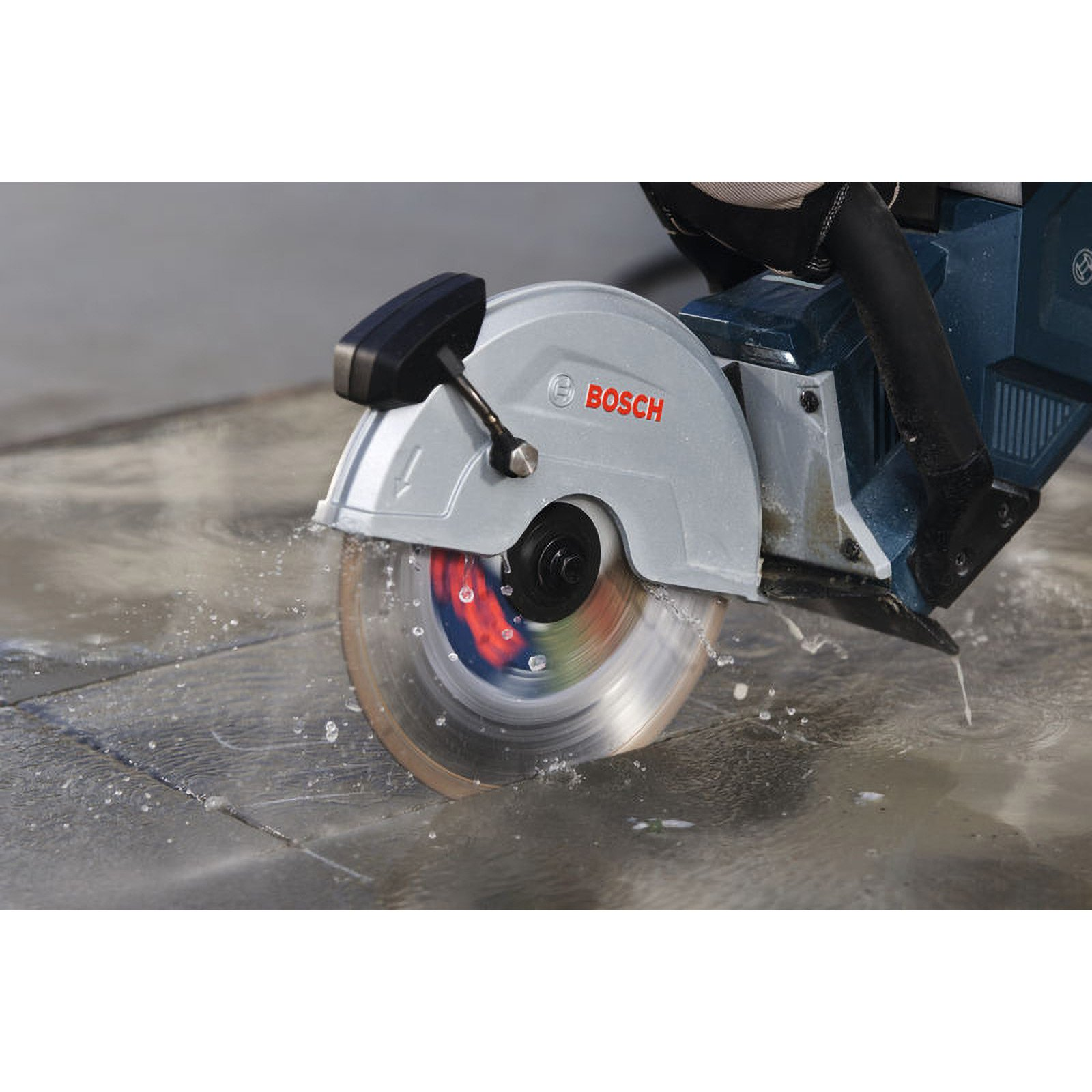 Ein Bosch-Trennschleifer schneidet nass durch Steinplatten, Wasser spritzt.