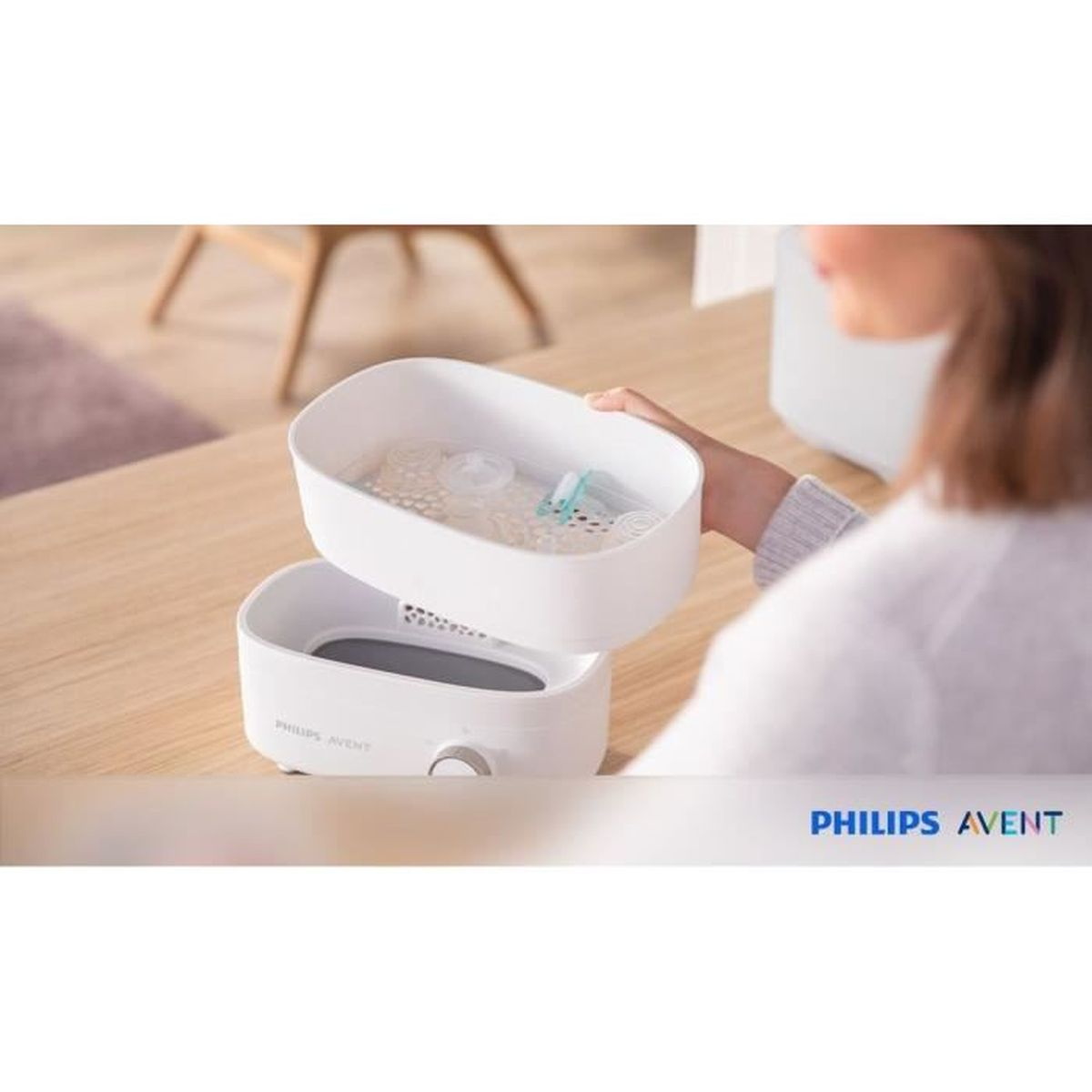 Eine Frau hält einen weißen Dampfsterilisator mit Babyflaschen-Zubehör.