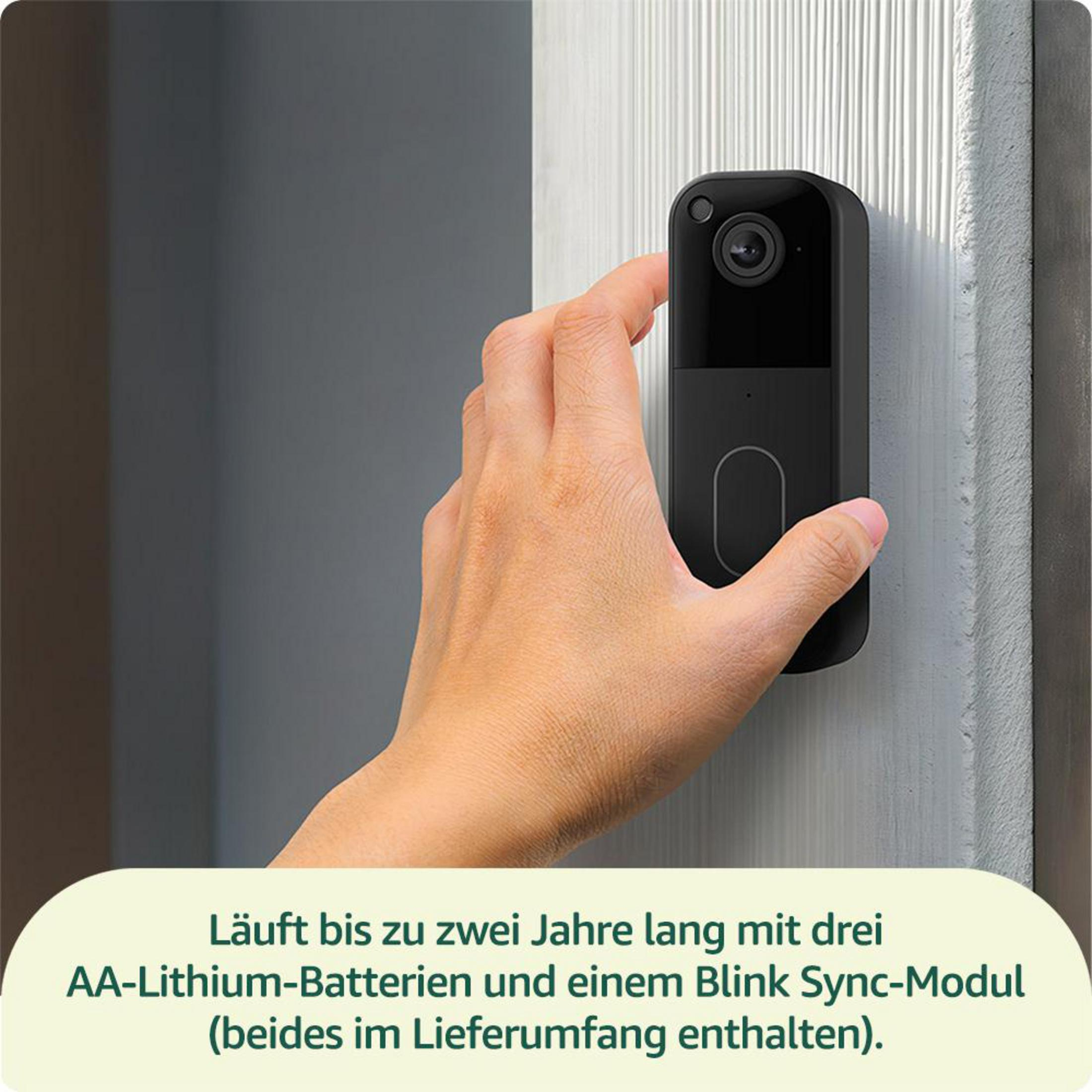 Eine Hand montiert eine schwarze Türklingelkamera an einer Wand.