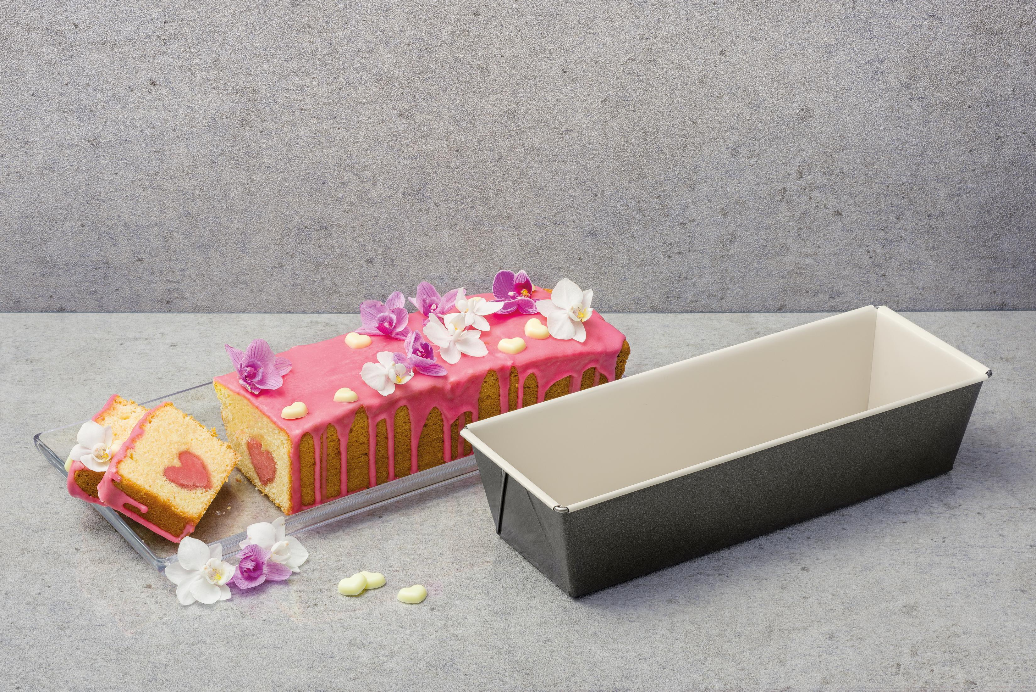 Ein Kuchen mit rosa Glasur und Orchideen, daneben eine leere Backform.
