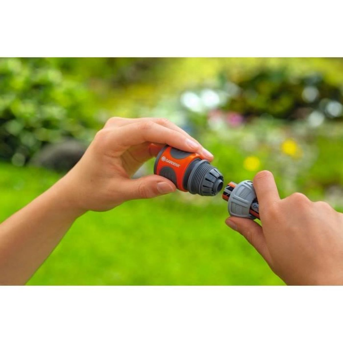 Hände verbinden Gartenschlauchstücke. Orange-grauer Verbinder wird angeschlossen.