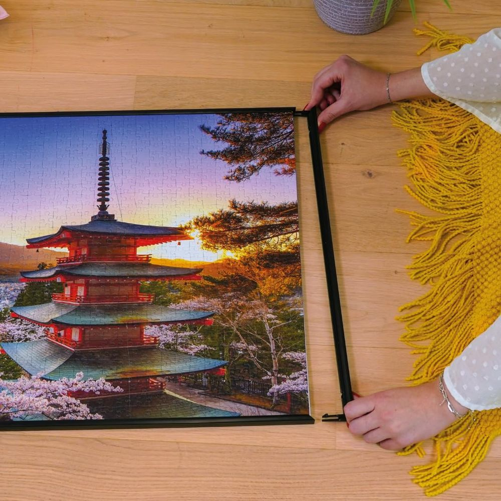 Eine Frau setzt ein Puzzle einer japanischen Pagode im Sonnenuntergang mit Kirschblüten zusammen.