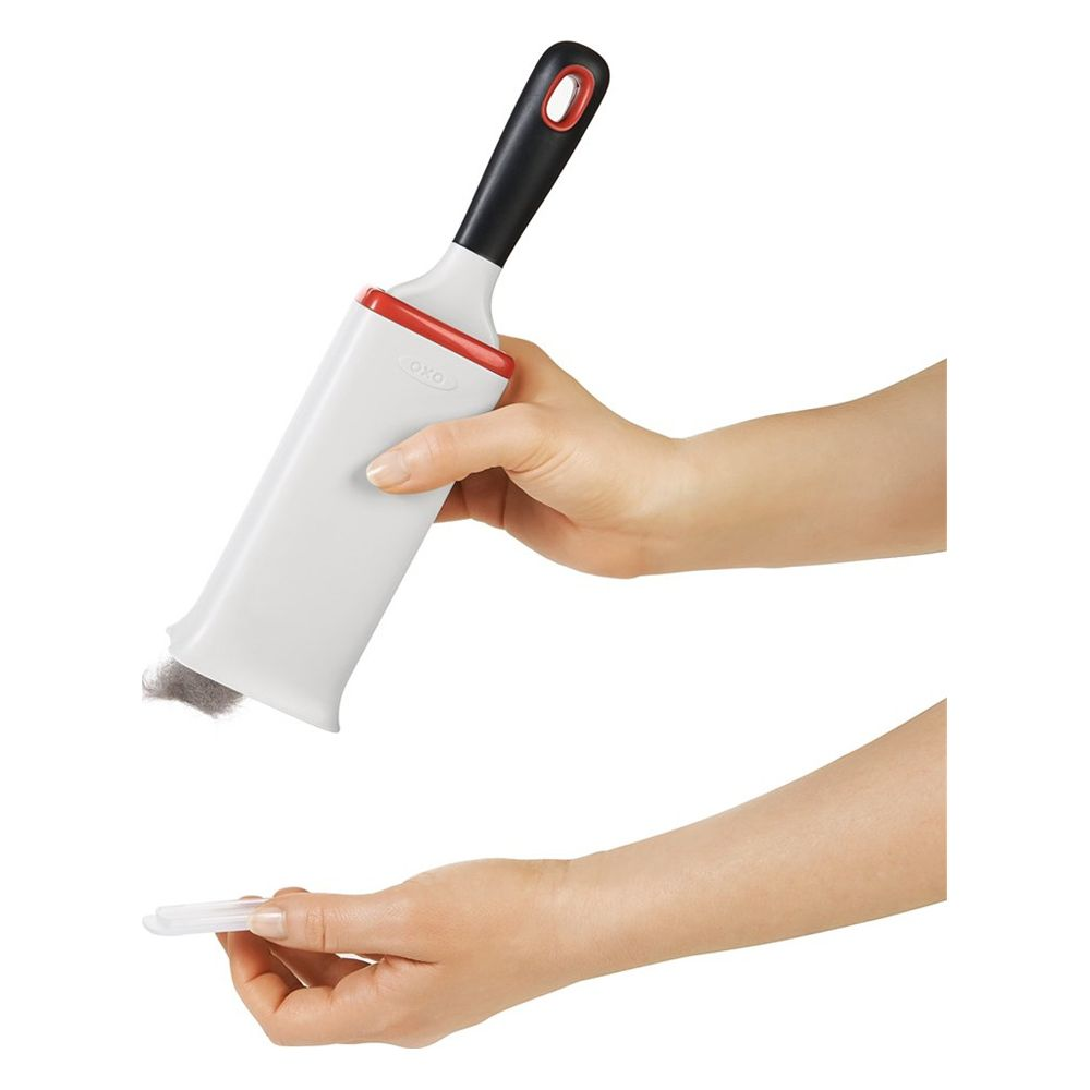 Eine Hand hält ein weißes und rotes Reinigungsgerät mit schwarzem Griff. Eine andere Hand hält ein kleines weißes Teil.