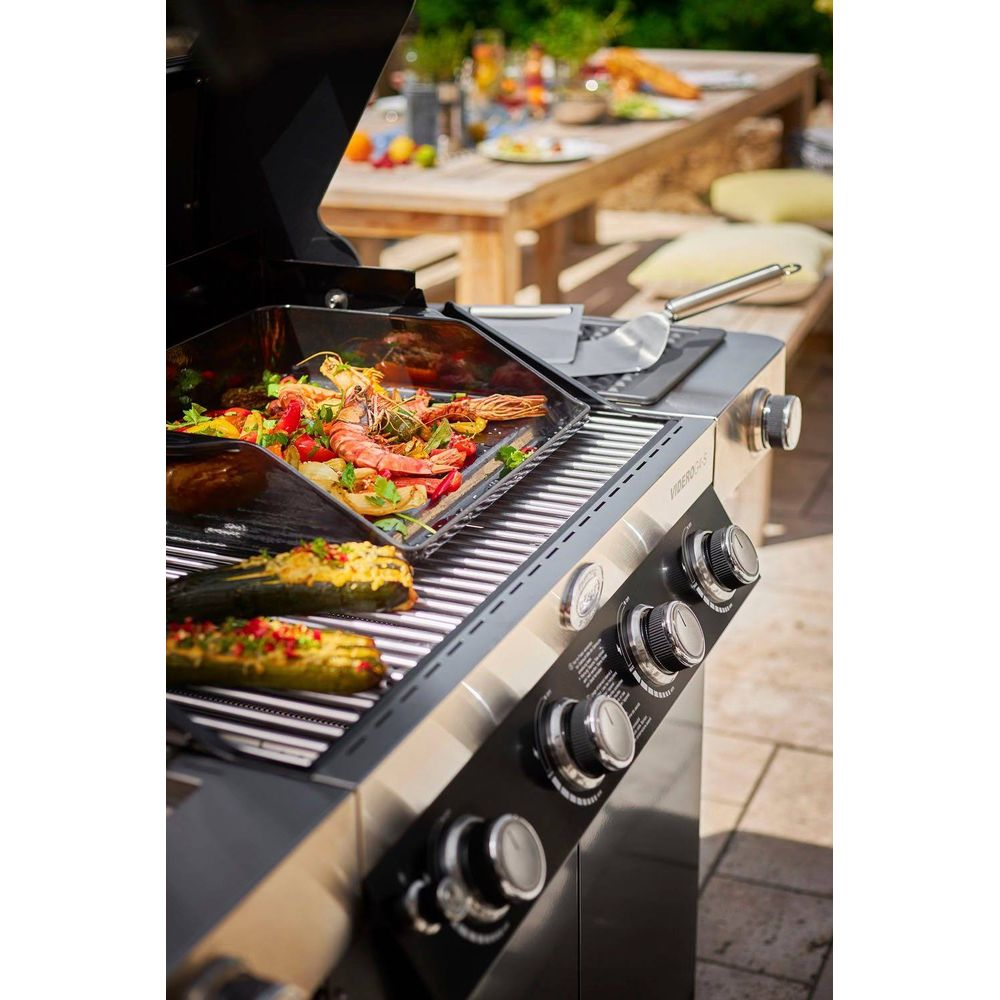 Ein Gasgrill mit Garnelen und Gemüse, und zwei Zucchinihälften auf den Rosten.