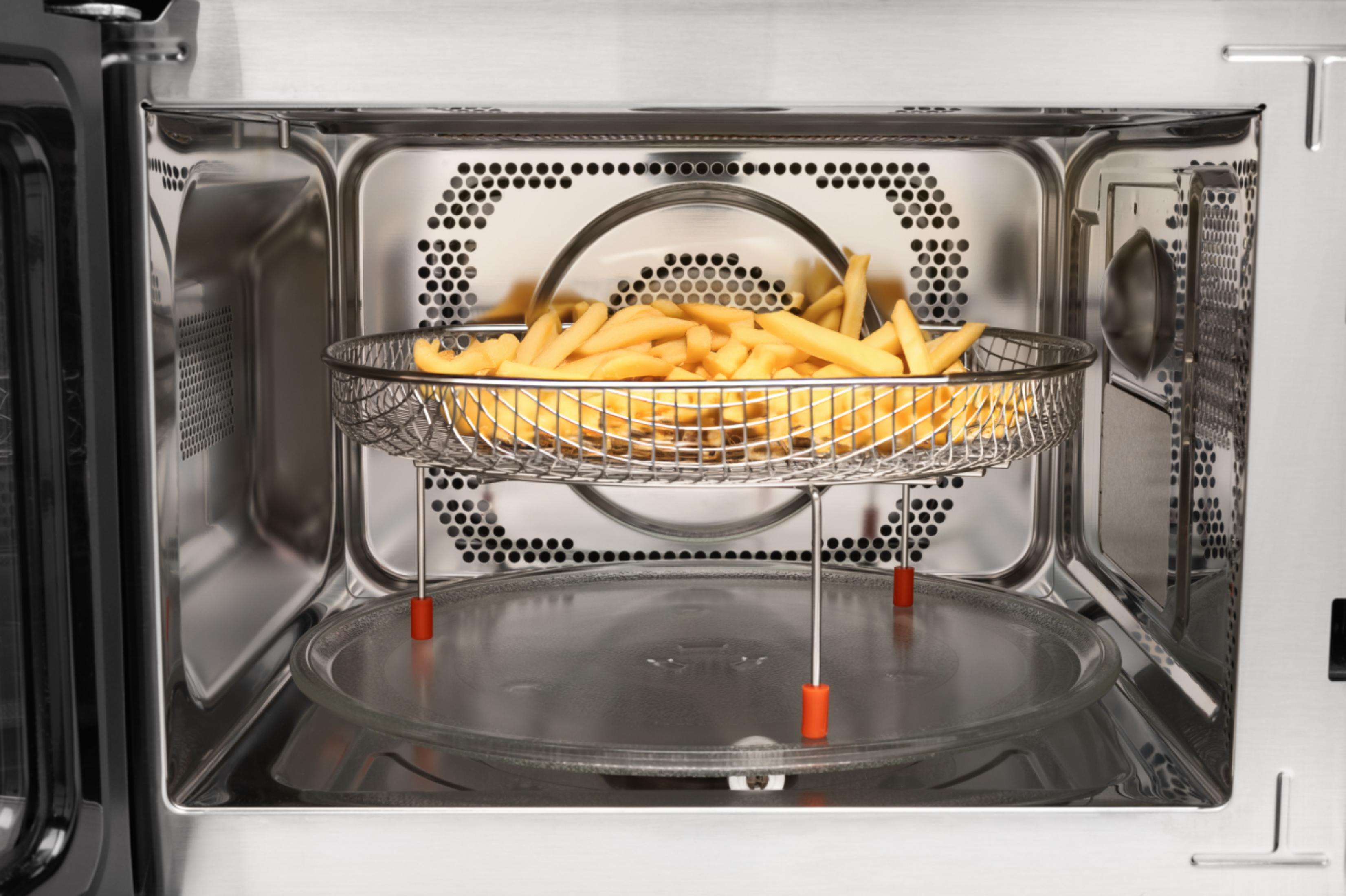 Ein Korb mit Pommes frites steht in einem offenen Mikrowellenofen.