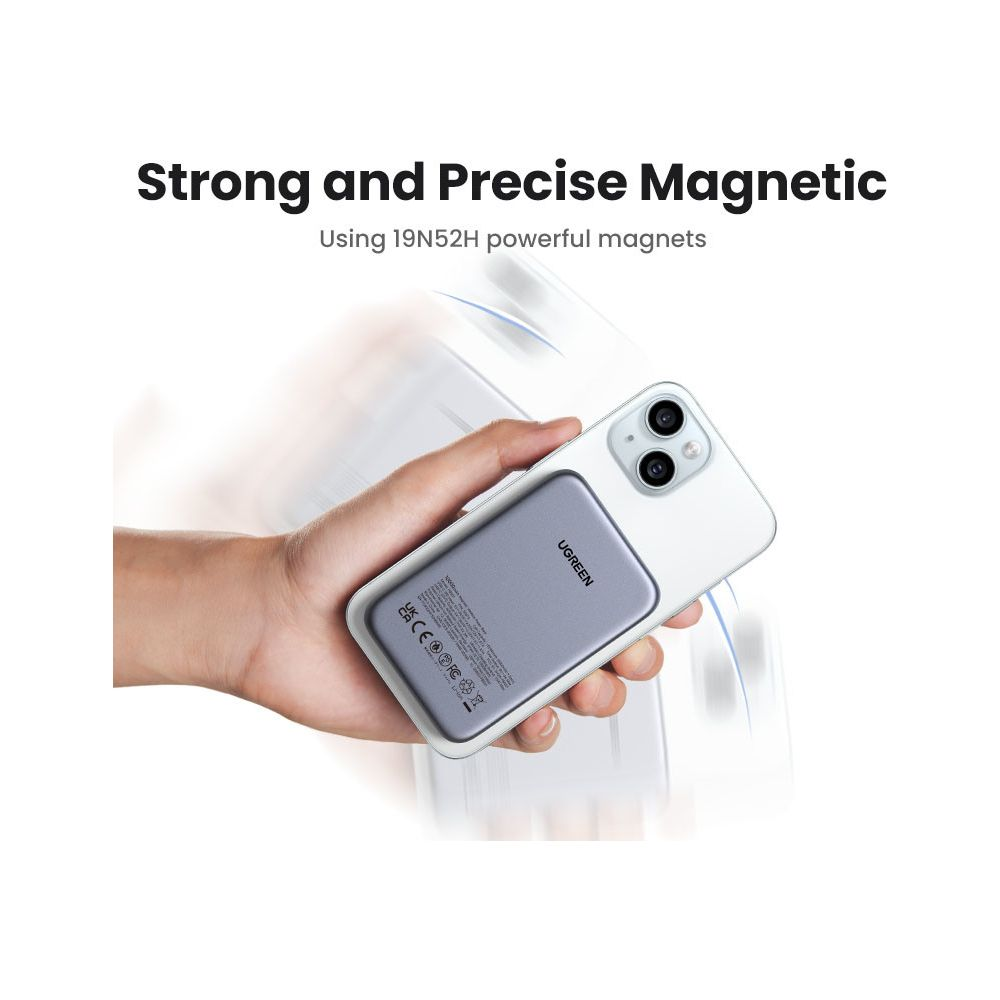 Gray magnetic power bank attached to a white iPhone. Hand holding the device.