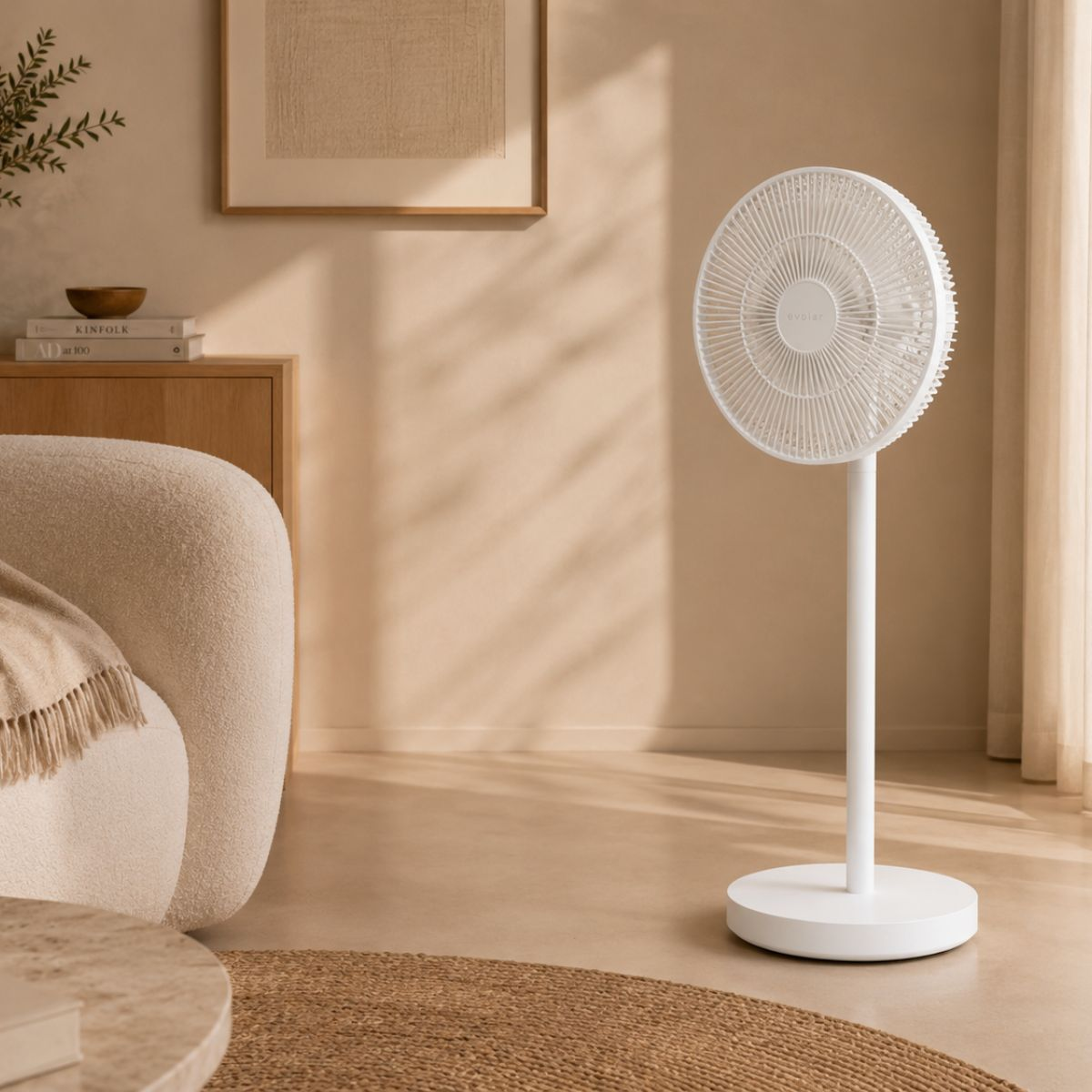 Een witte staande ventilator staat in een kamer met beige muren, een stoel en een salontafel.