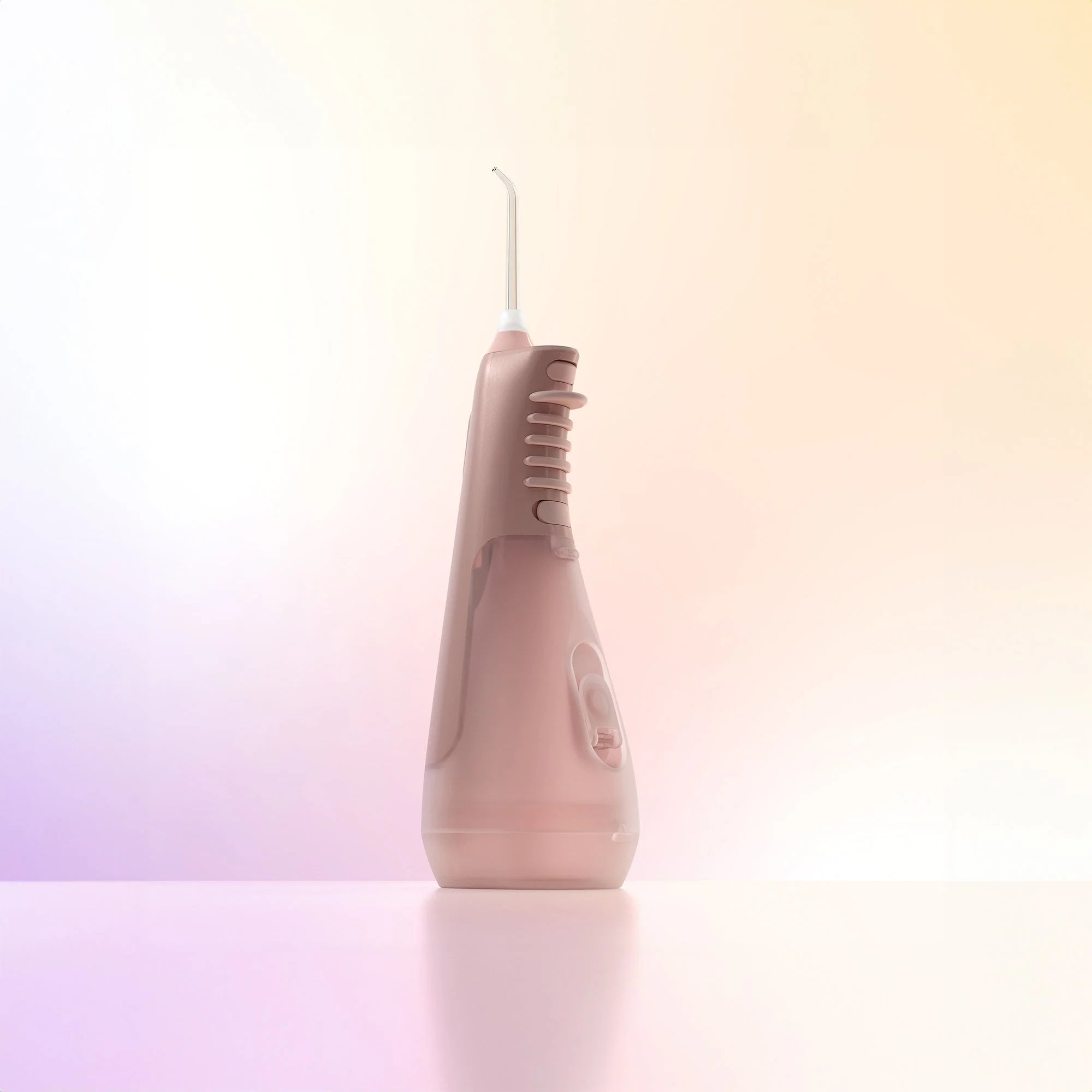 Una boquilla de irrigador bucal rosa sobre una superficie clara.