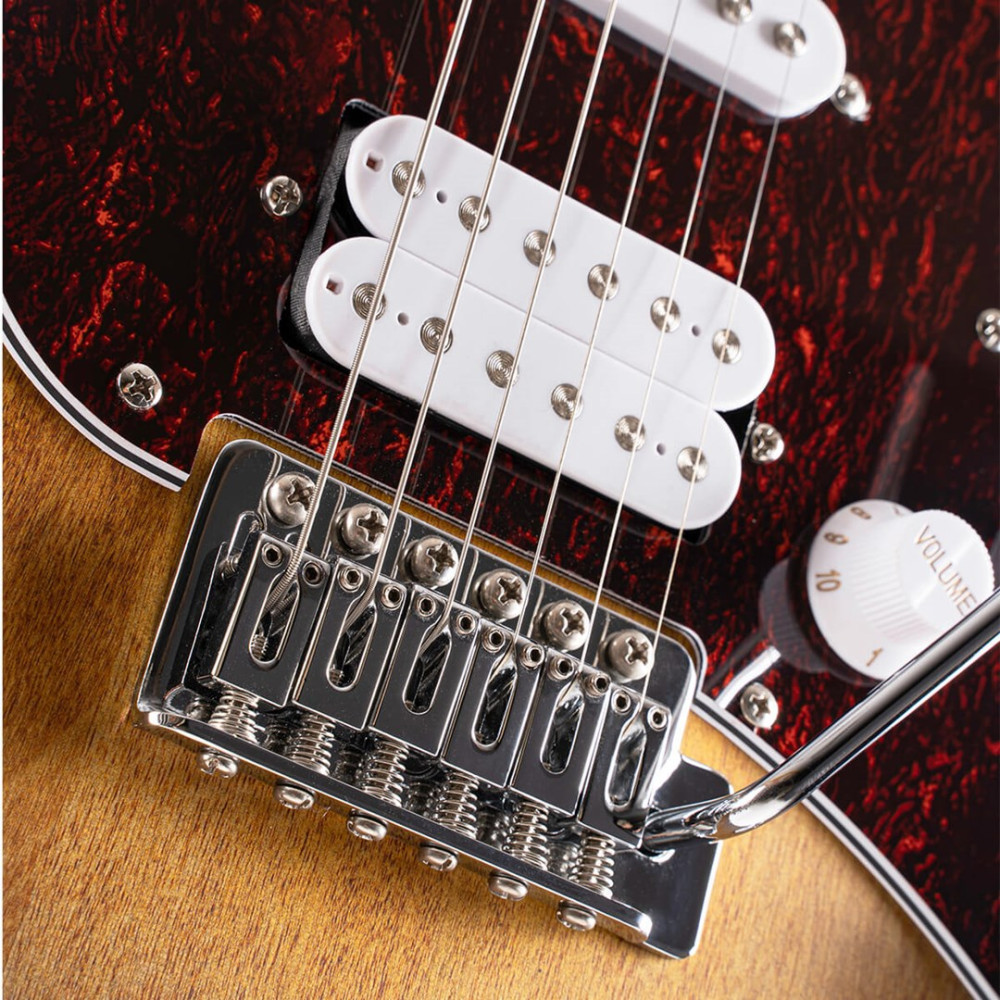 Zbliżenie na mostek gitary, przetworniki, pokrętło głośności i czerwony pickguard imitujący żółwia.