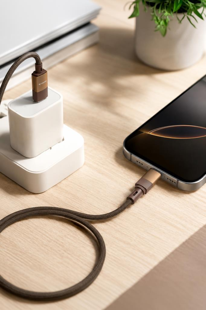 Bir akıllı telefon, kahverengi bir kabloyla beyaz bir adaptörden şarj oluyor.