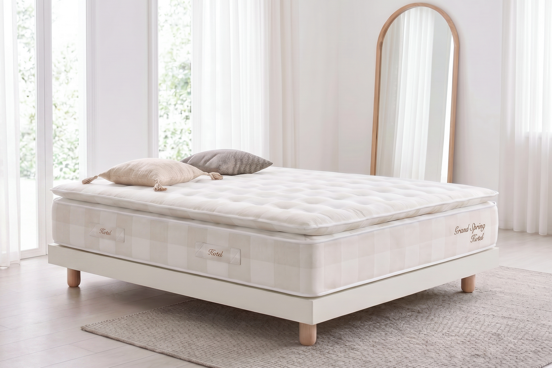 Una cama blanca con colchón y almohadas, junto a un espejo.