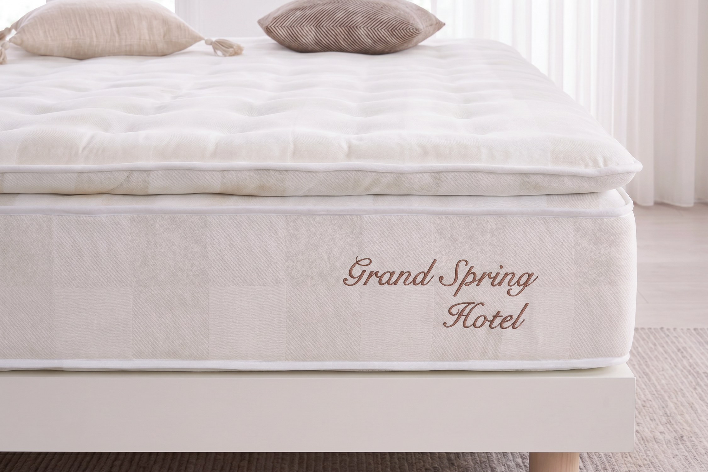 Un colchón blanco con "Grand Spring Hotel" bordado en el lateral. Dos almohadas encima.