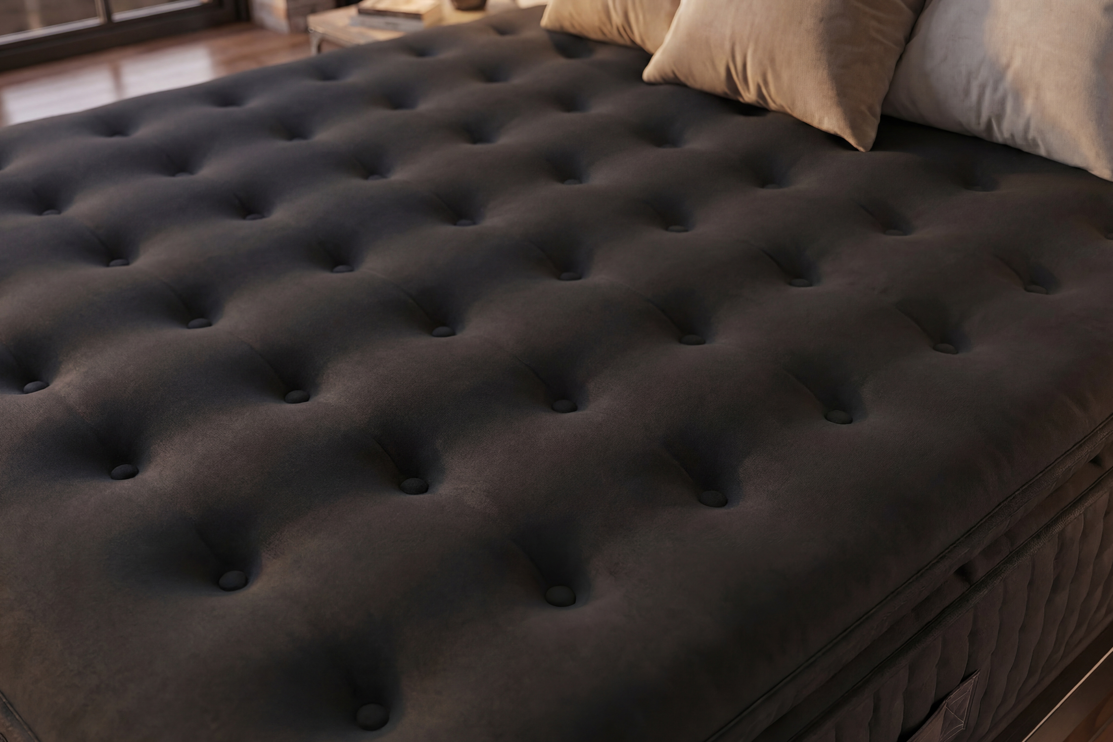 Un colchón oscuro con botones y dos almohadas en una cama.