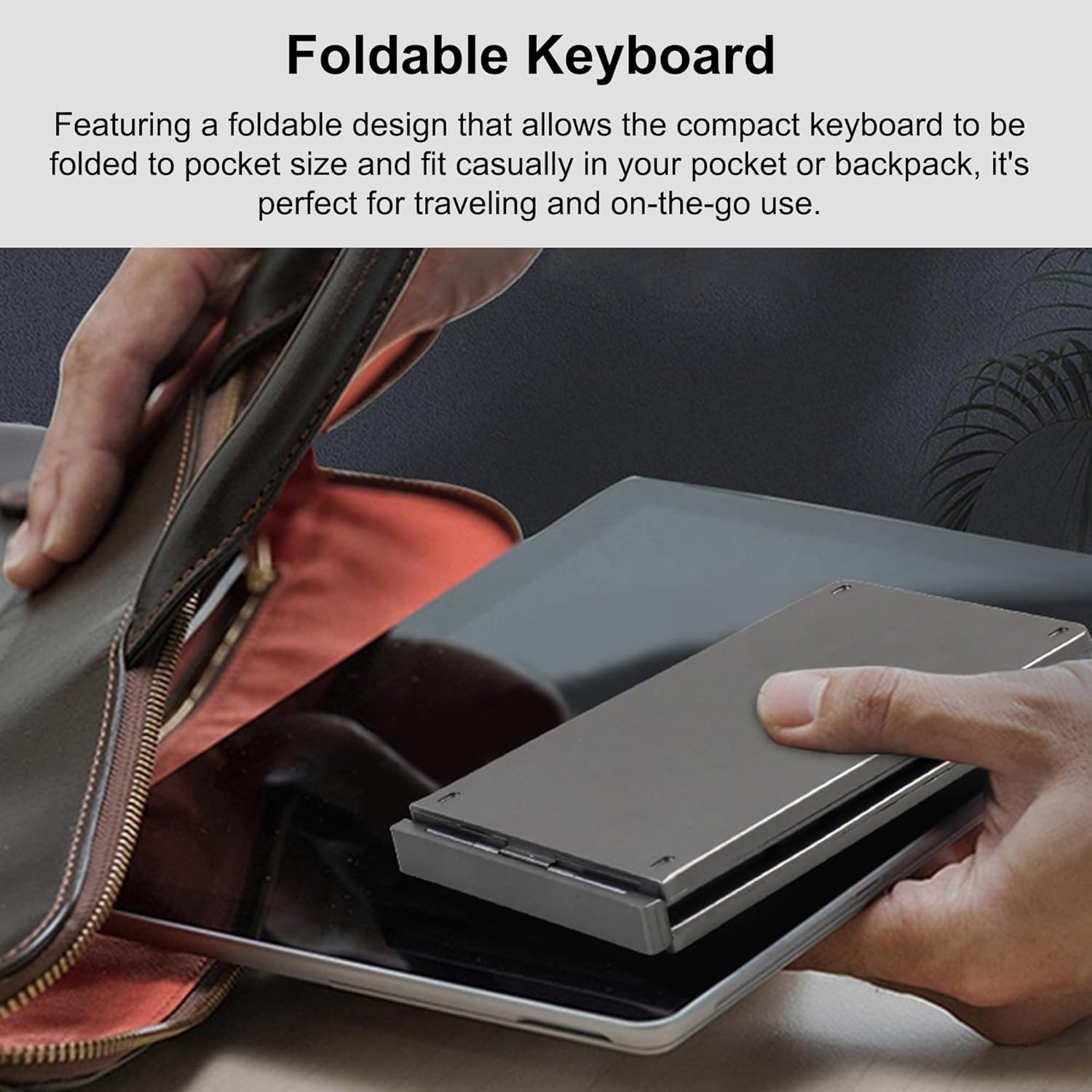 Eine Hand hält eine zusammengeklappte graue Tastatur über einem Tablet.